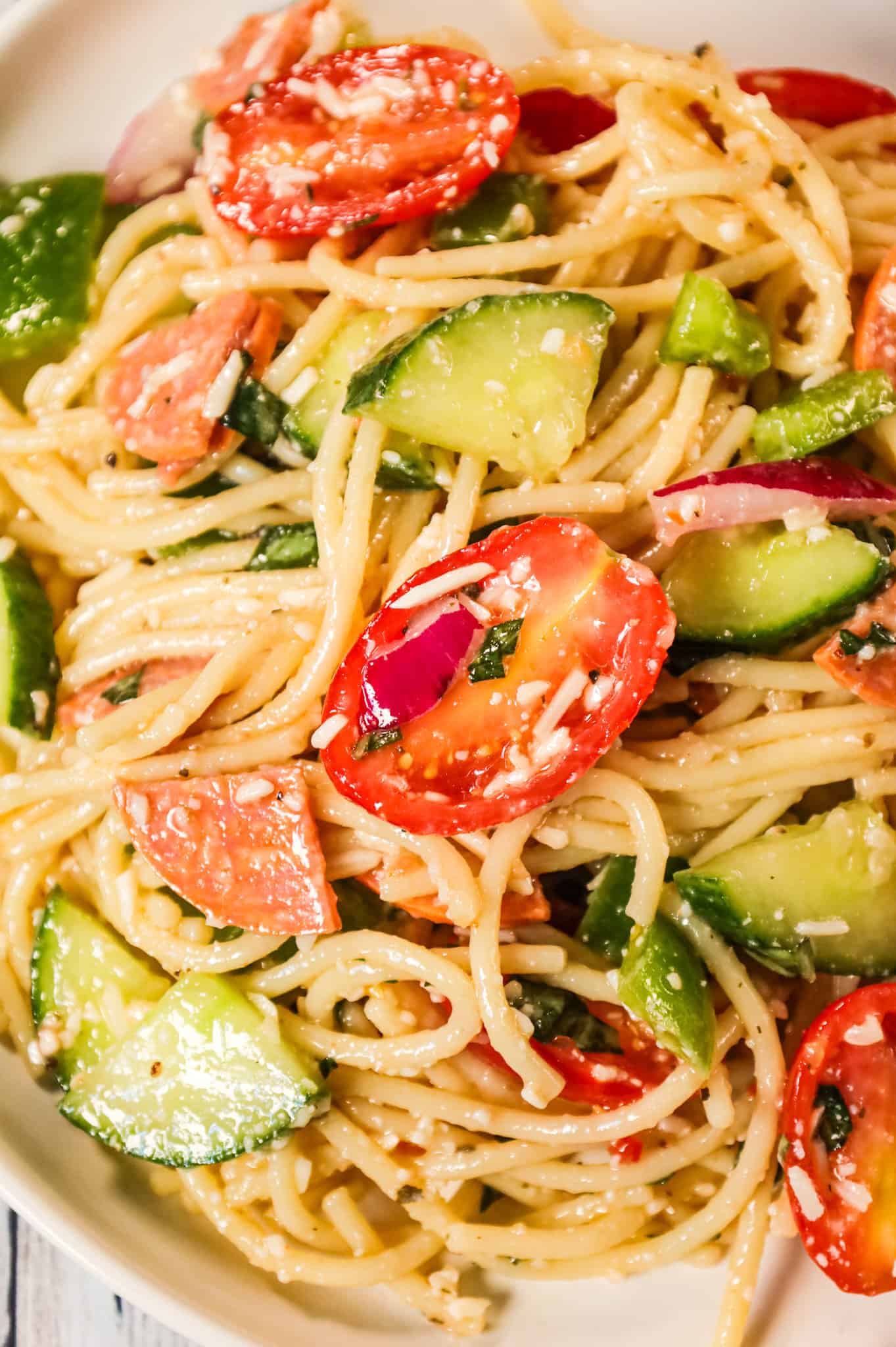 Spaghetti Salad is a tasty pasta salad recipe loaded with cucumbers, grape tomatoes, green peppers, red onions, pepperoni and grated parmesan all tossed in Italian dressing.