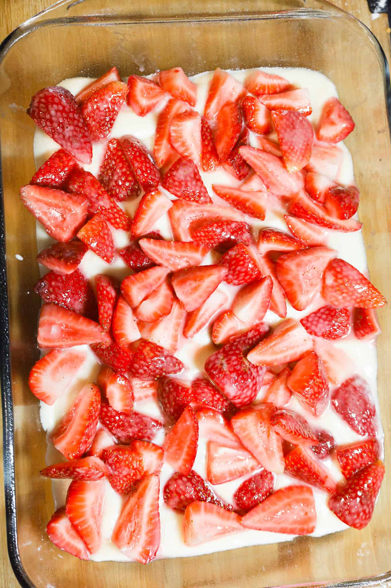 chopped strawberries on top batter in a baking dish