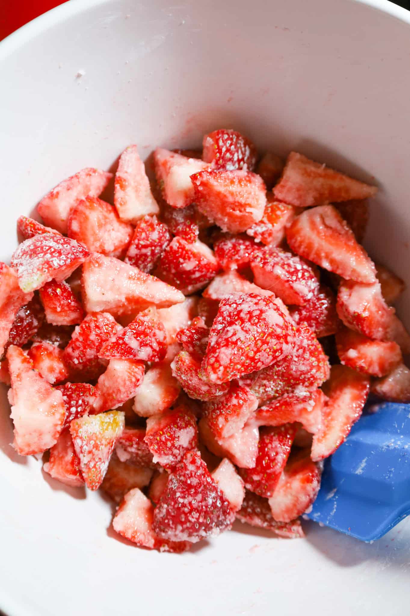 quartered strawberries coated in sugar and corn starch in a mixing bowl
