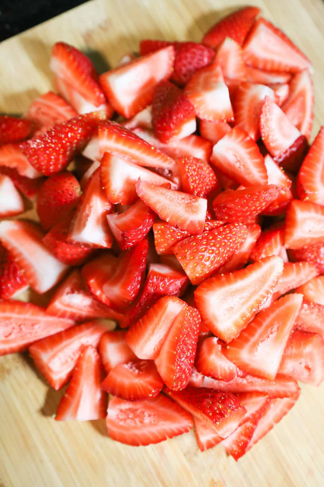 quartered strawberries on a cutting board