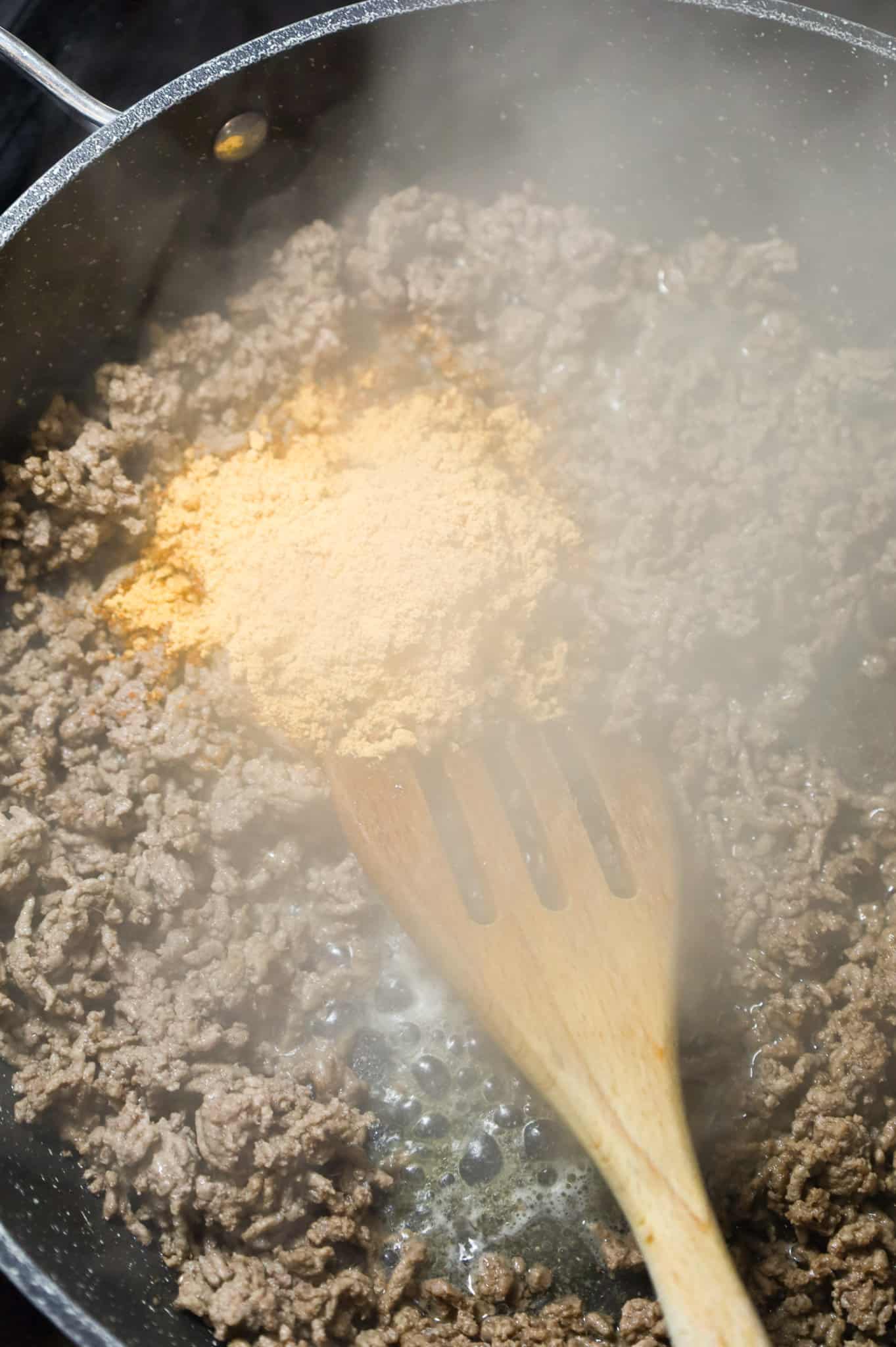 taco seasoning on top of cooked ground beef in a skillet