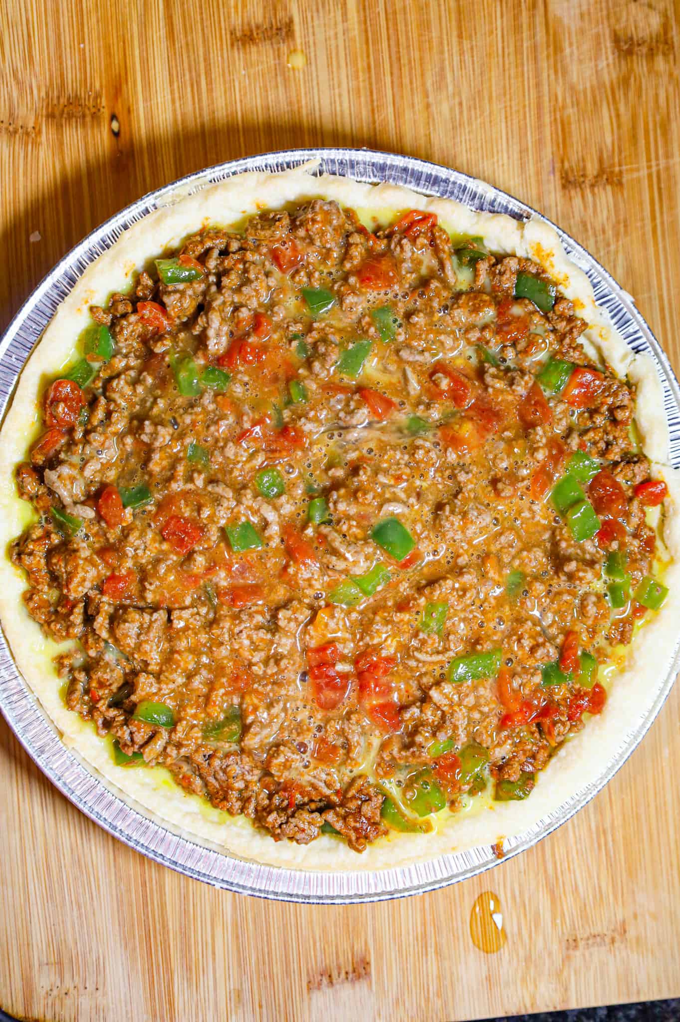 eggs poured into ground beef mixture in a pie crust