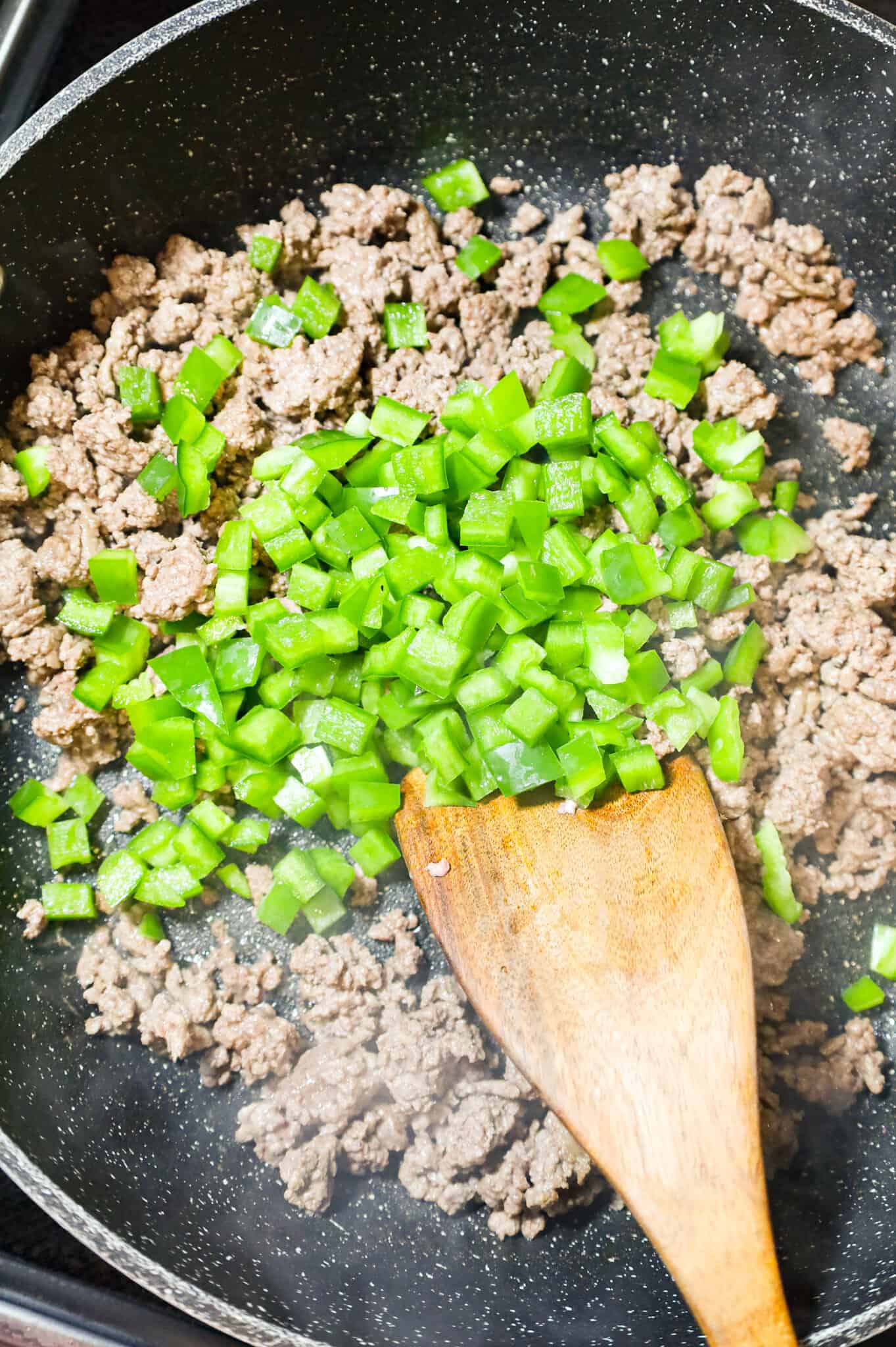 diced green onions on top of ground beef in a skillet