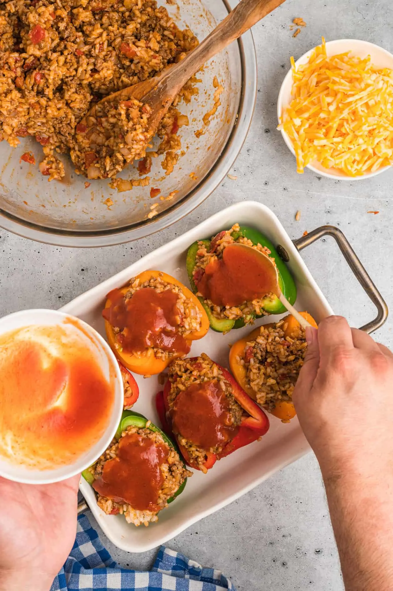 taco sauce spooned over stuffed peppers in a baking pan