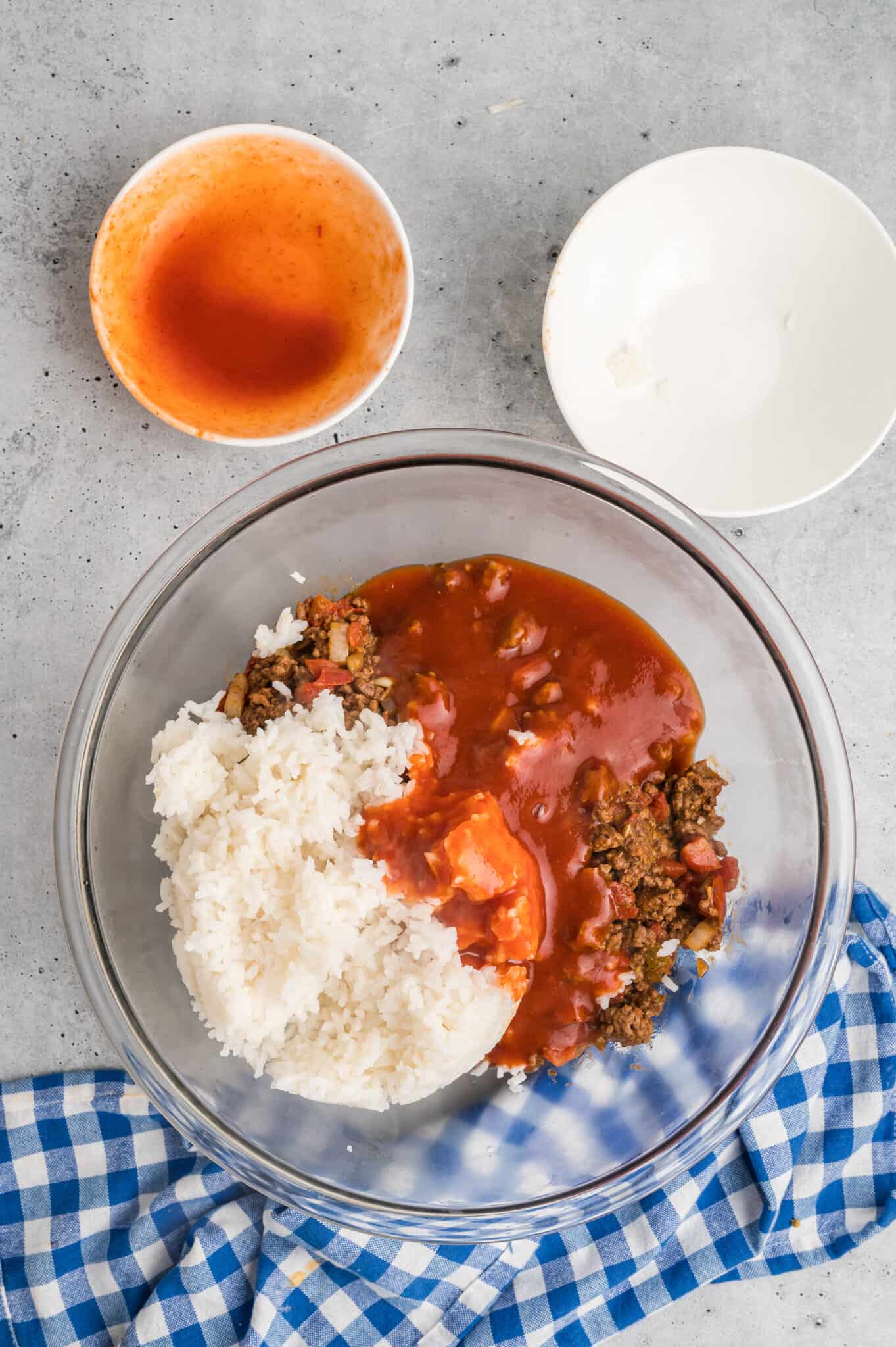 cooked white rice, cooked ground beef and taco sauce in a mixing bowl