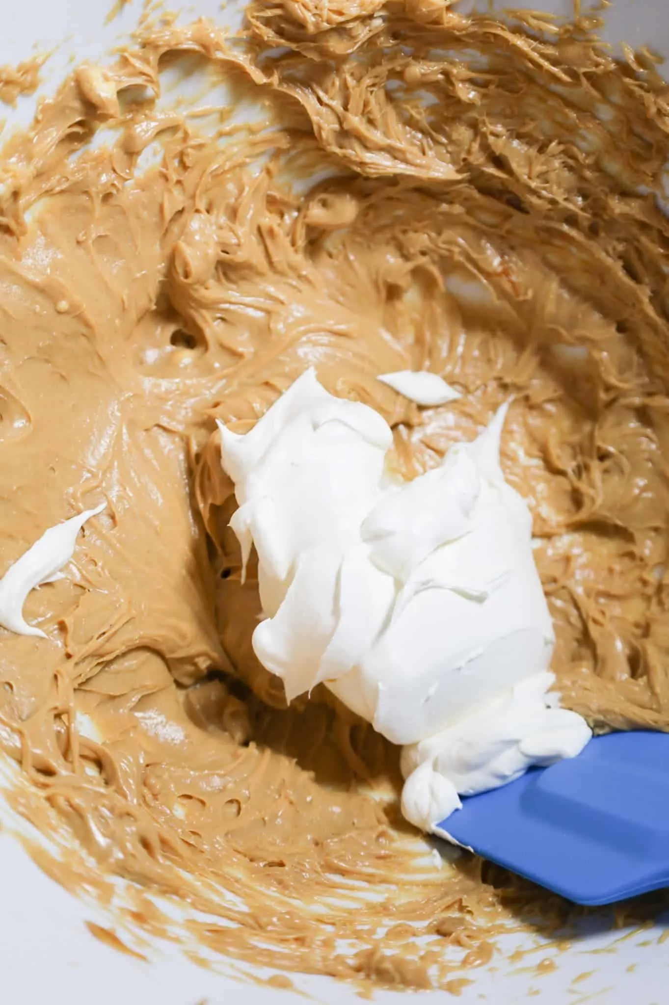 Cool Whip on top of cream cheese and dulce de leche mixture in a mixing bowl