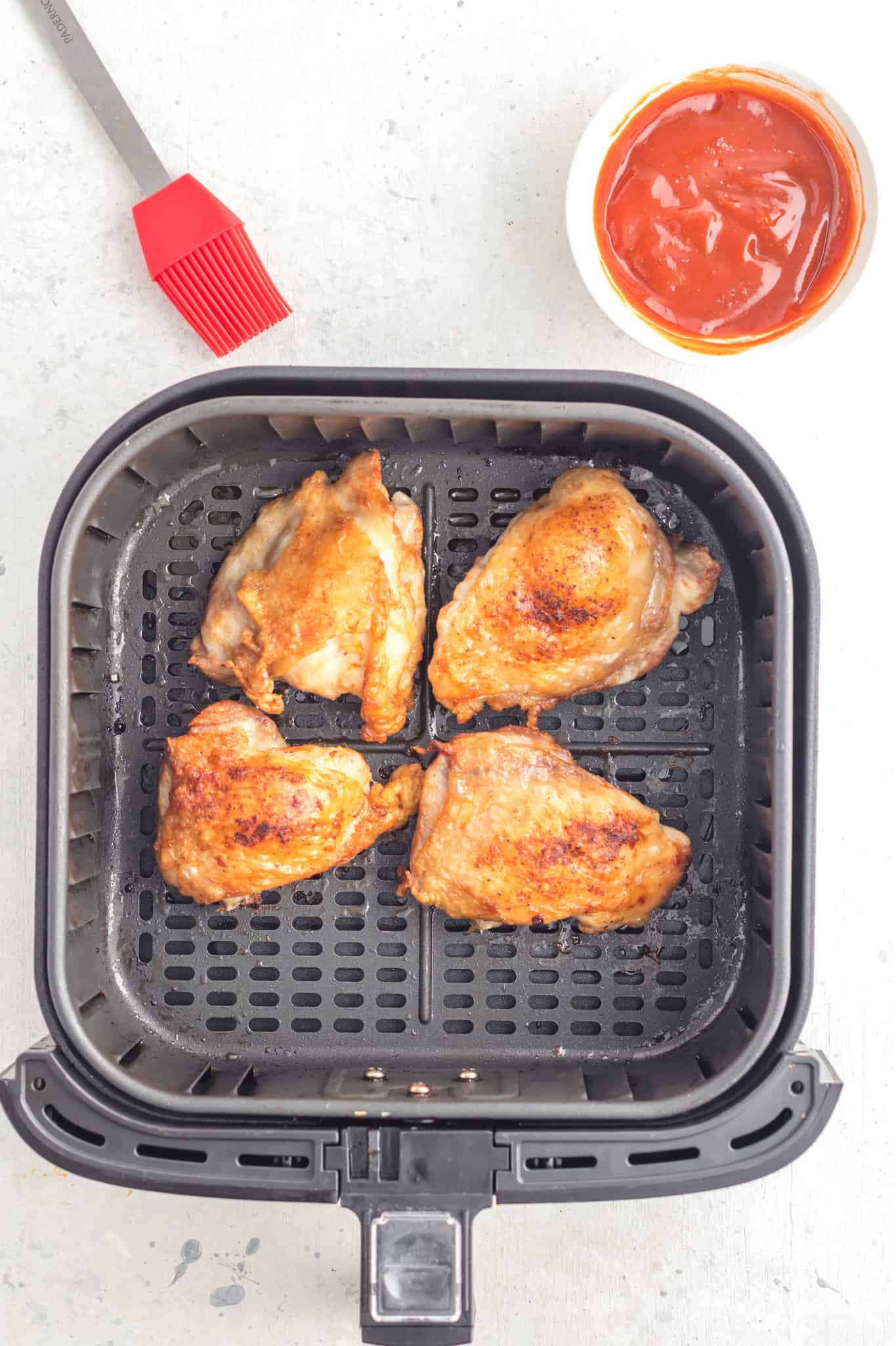 chicken thighs cooking in an air fryer