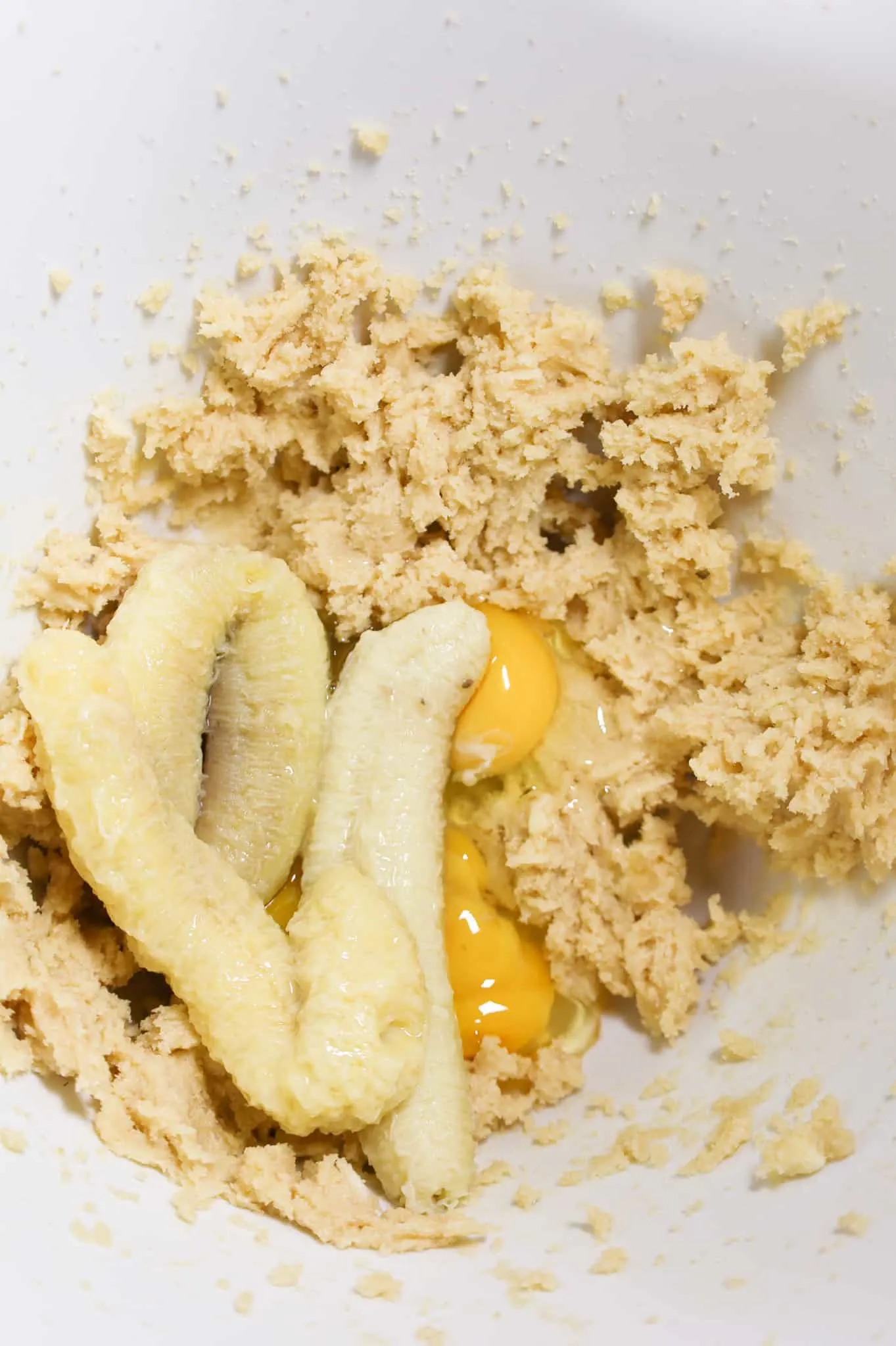 eggs and ripe bananas added to a bowl with creamed butter and sugar mixture in a mixing bowl