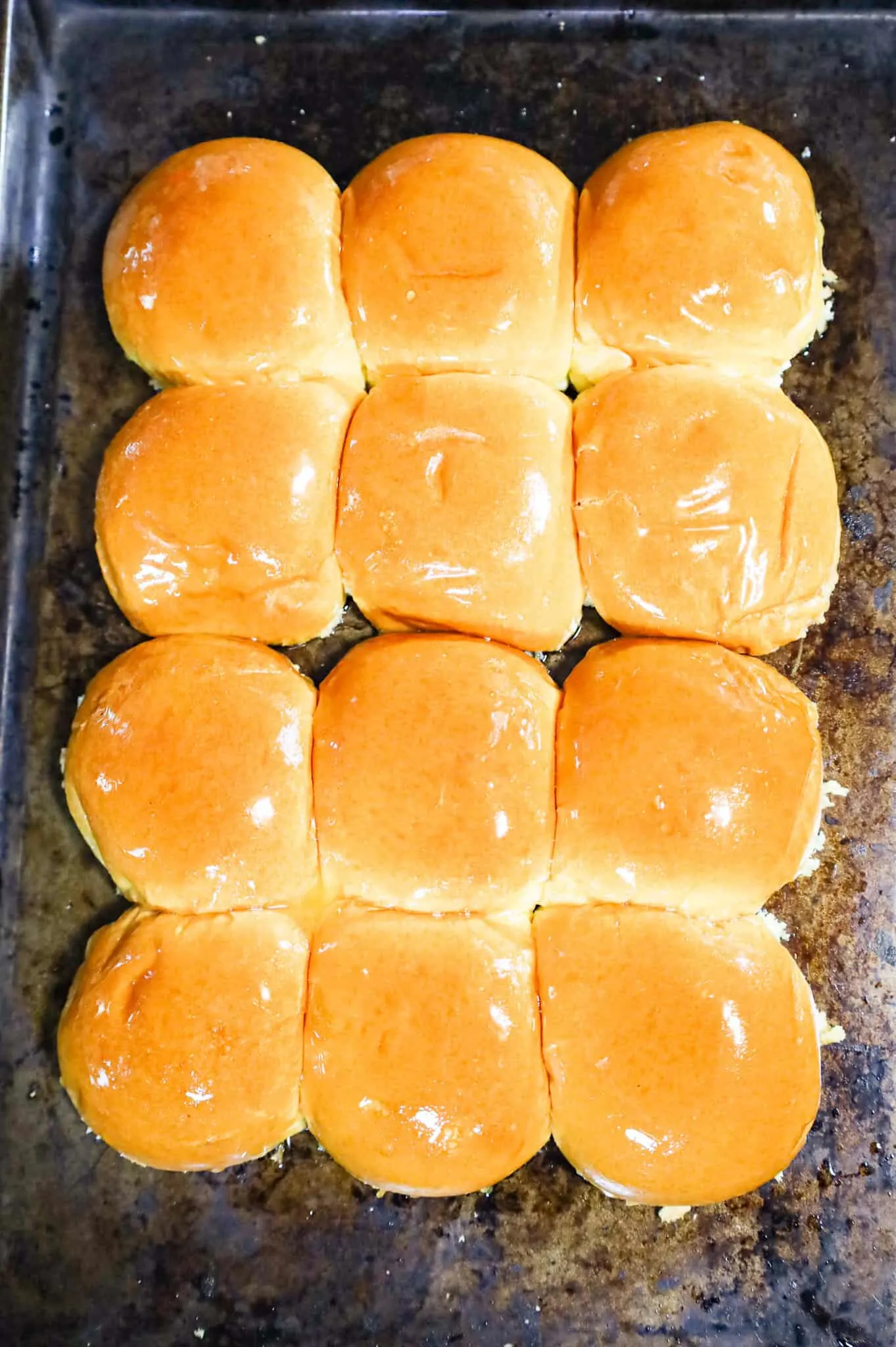 butter brushed top buns on a baking sheet