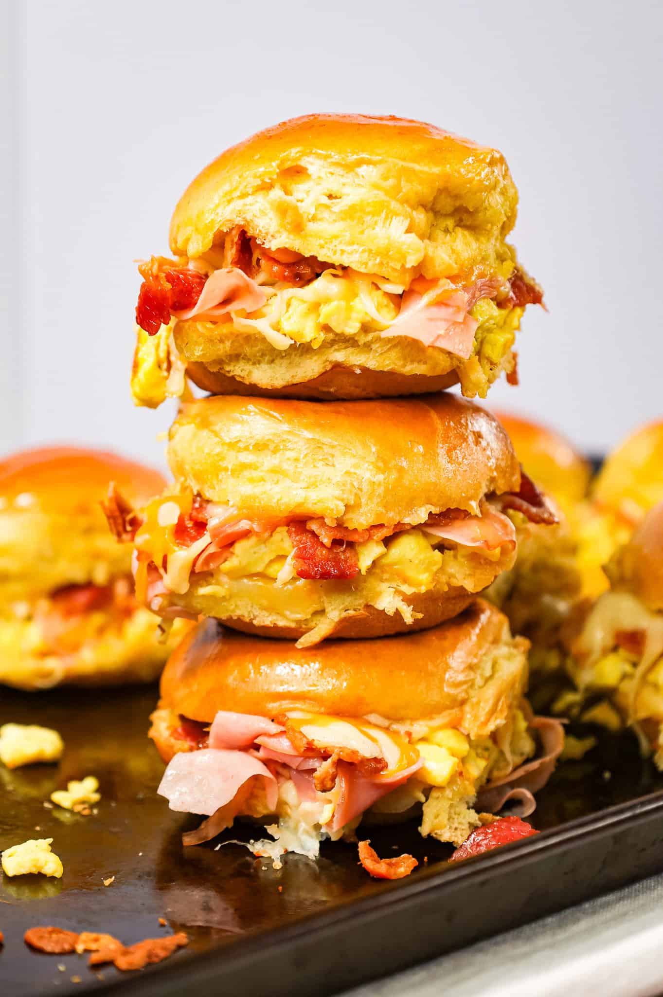 Breakfast Sliders are small pull apart breakfast sandwiches loaded with scrambled eggs, ham, bacon and cheese.