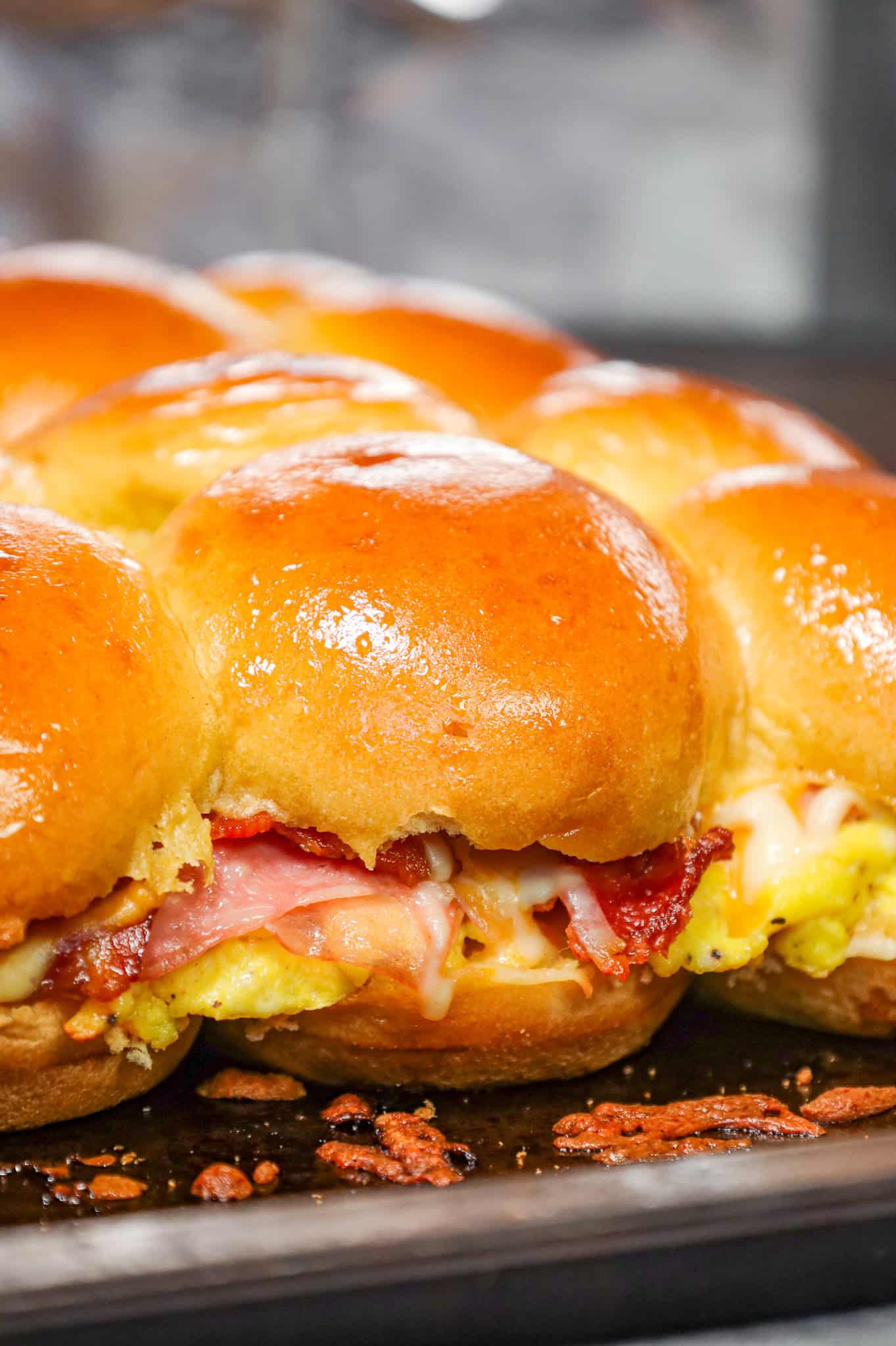 Breakfast Sliders are small pull apart breakfast sandwiches loaded with scrambled eggs, ham, bacon and cheese.