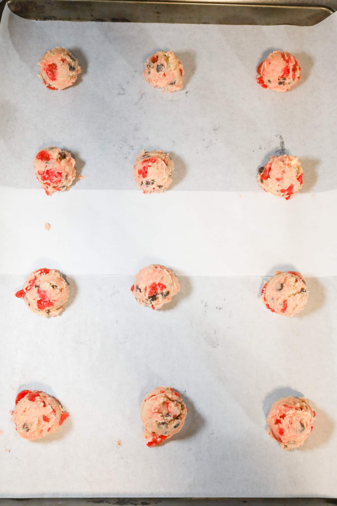 cherry chocolate chip cookie dough balls on a parchment lined baking sheet