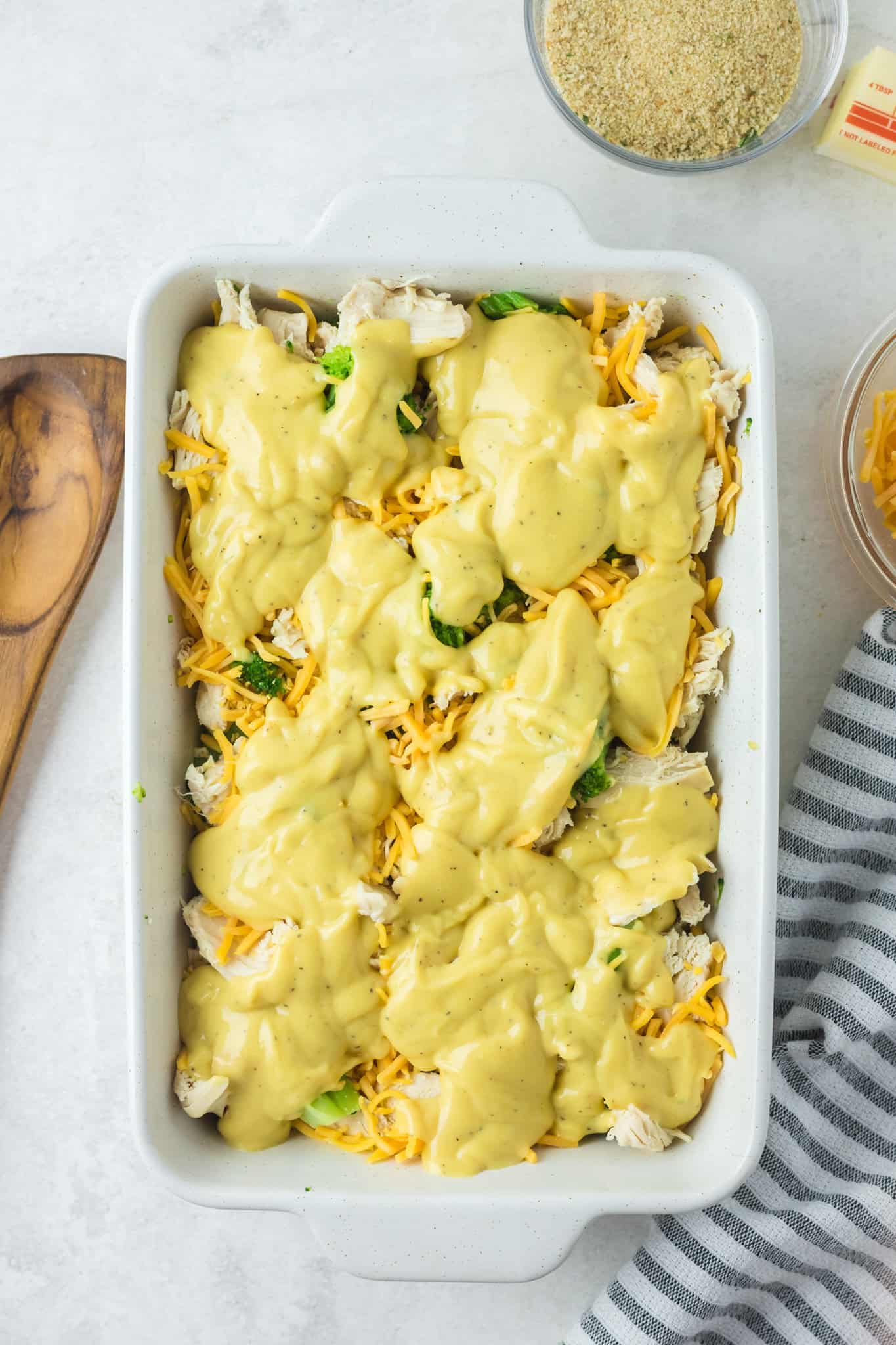 soup mixture spooned over cheese, chicken and broccoli in a baking dish