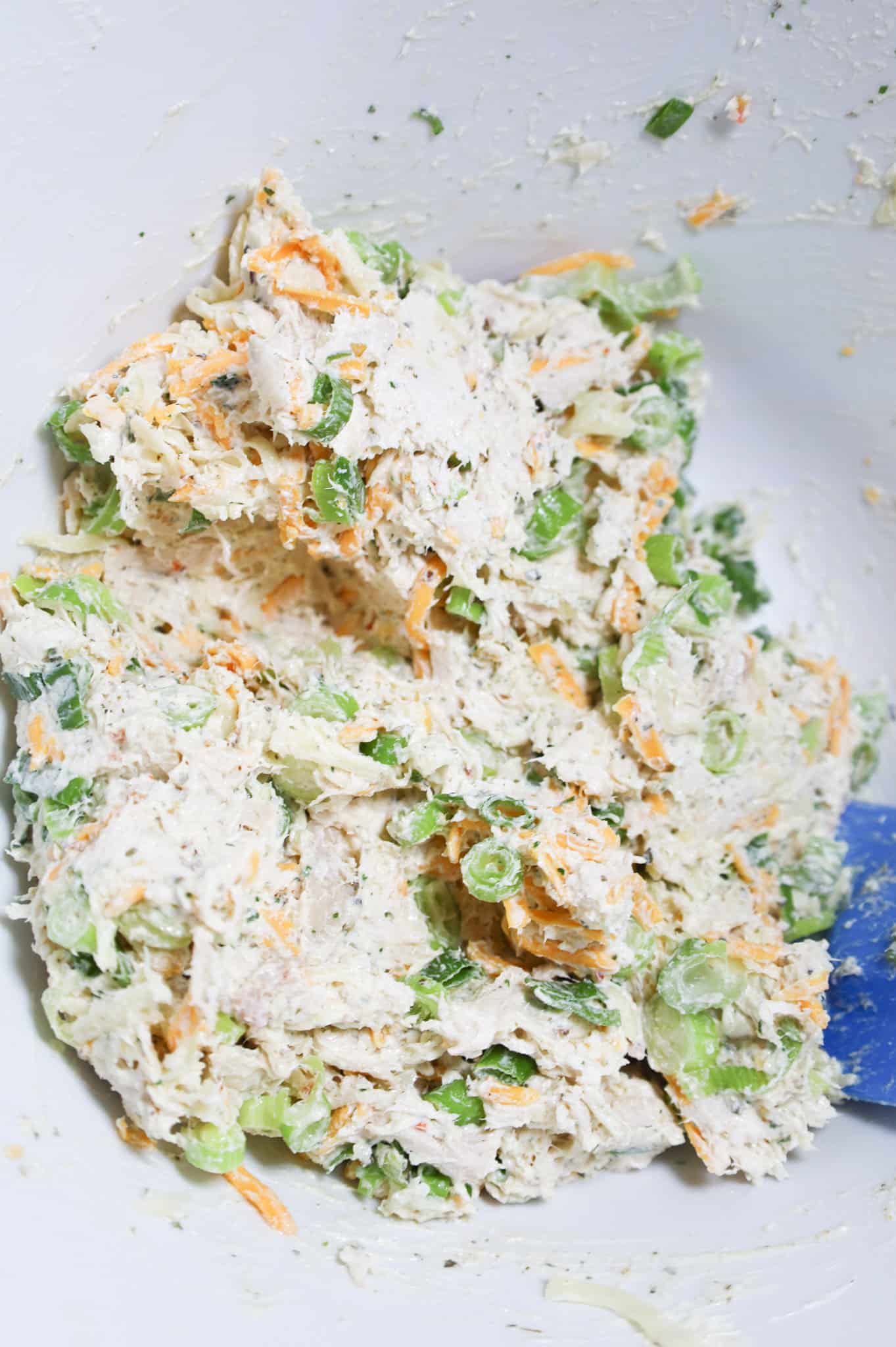 creamy chicken mixture with cheese and green onions in a mixing bowl