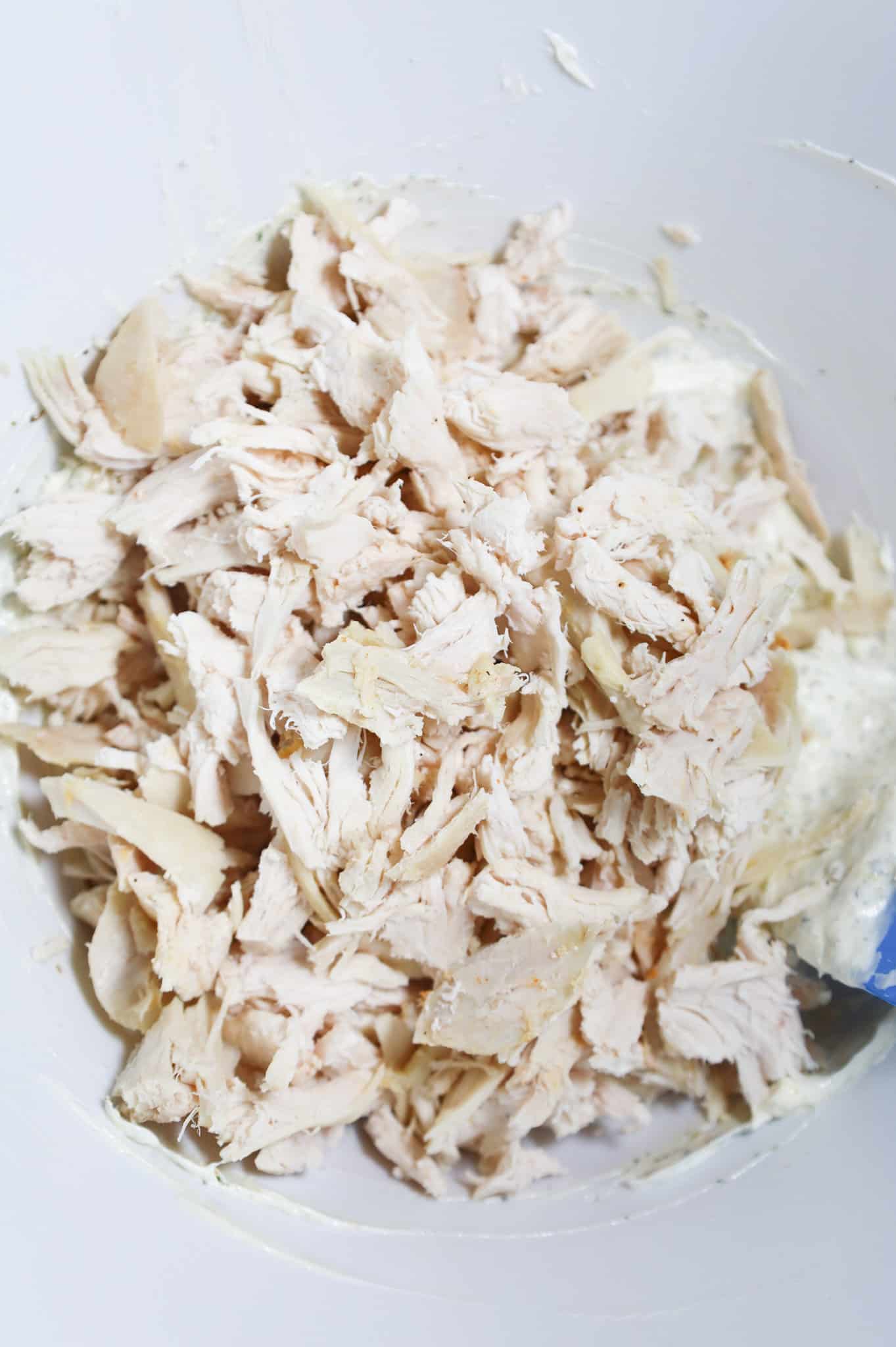 shredded chicken added to bowl with sour cream and mayo mixture