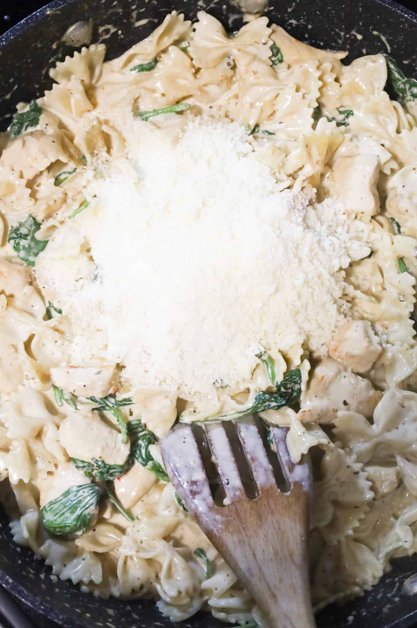 shredded parmesan cheese on top of alfredo pasta in a skillet