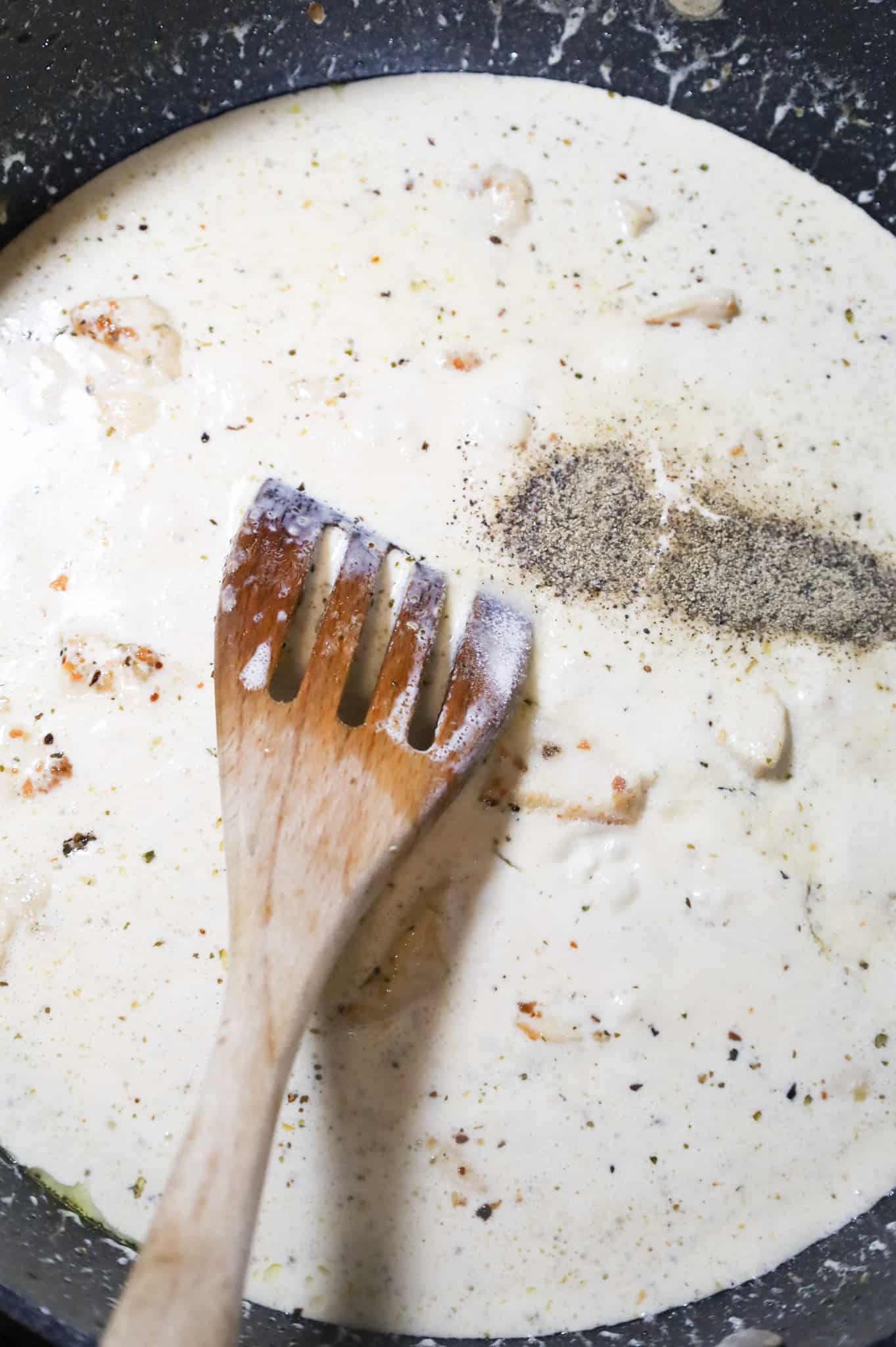 salt, pepper and heavy cream added to a skillet with cooked chicken breast chunks