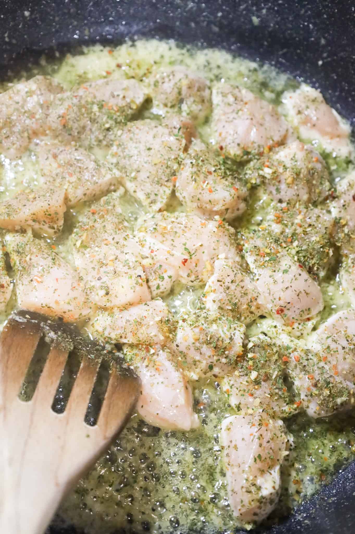 Italian seasoning on chicken breast chunks in a skillet