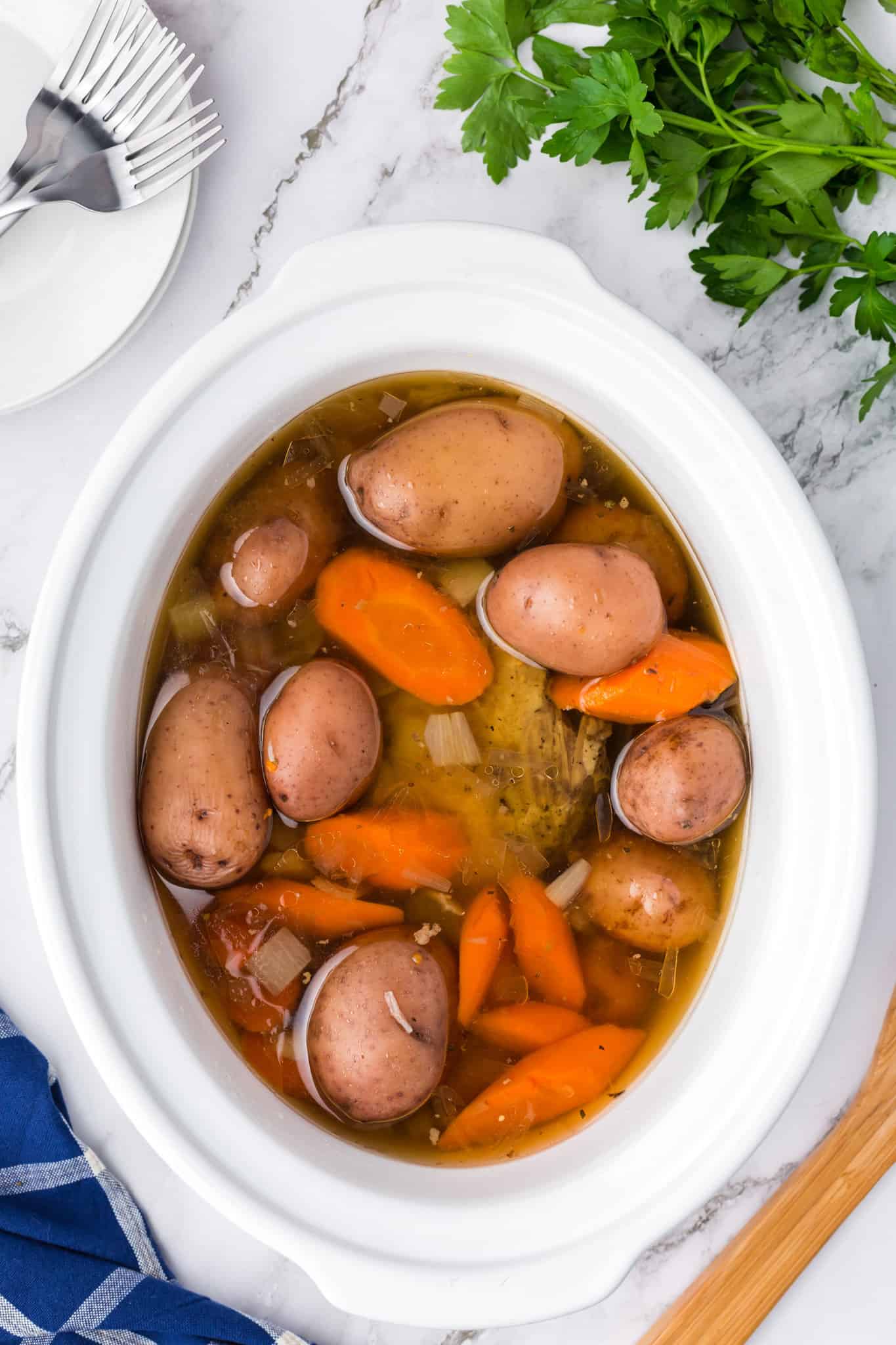 potatoes and carrots on top of corned beef brisket in a crock pot