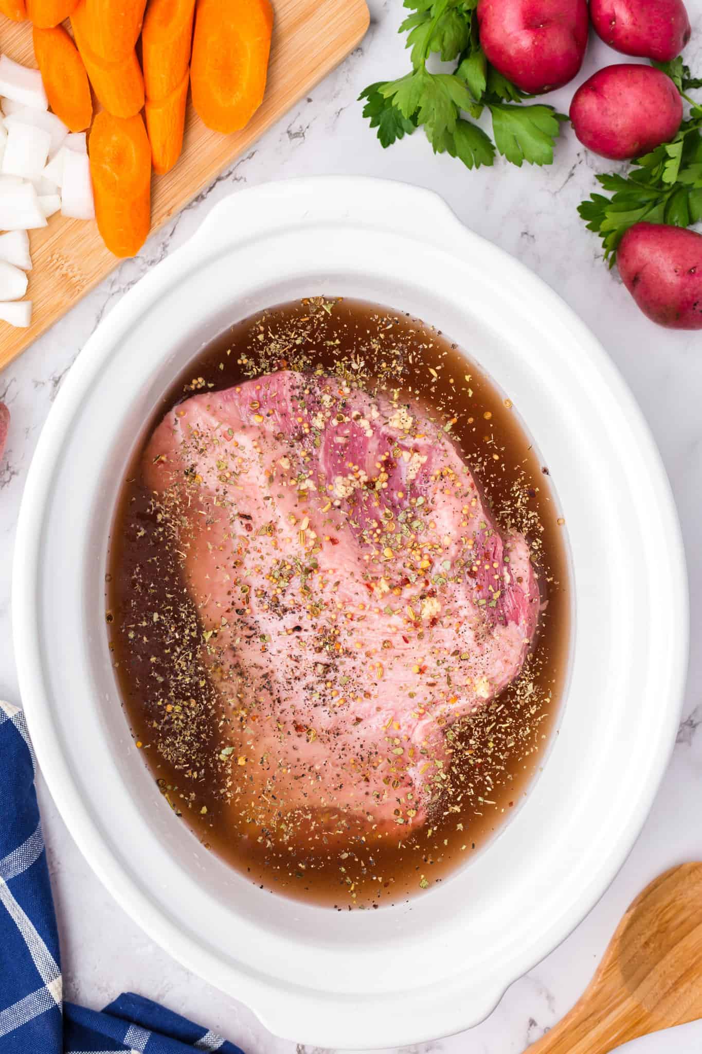 potatoes and carrots on top of corned beef brisket in a crock pot