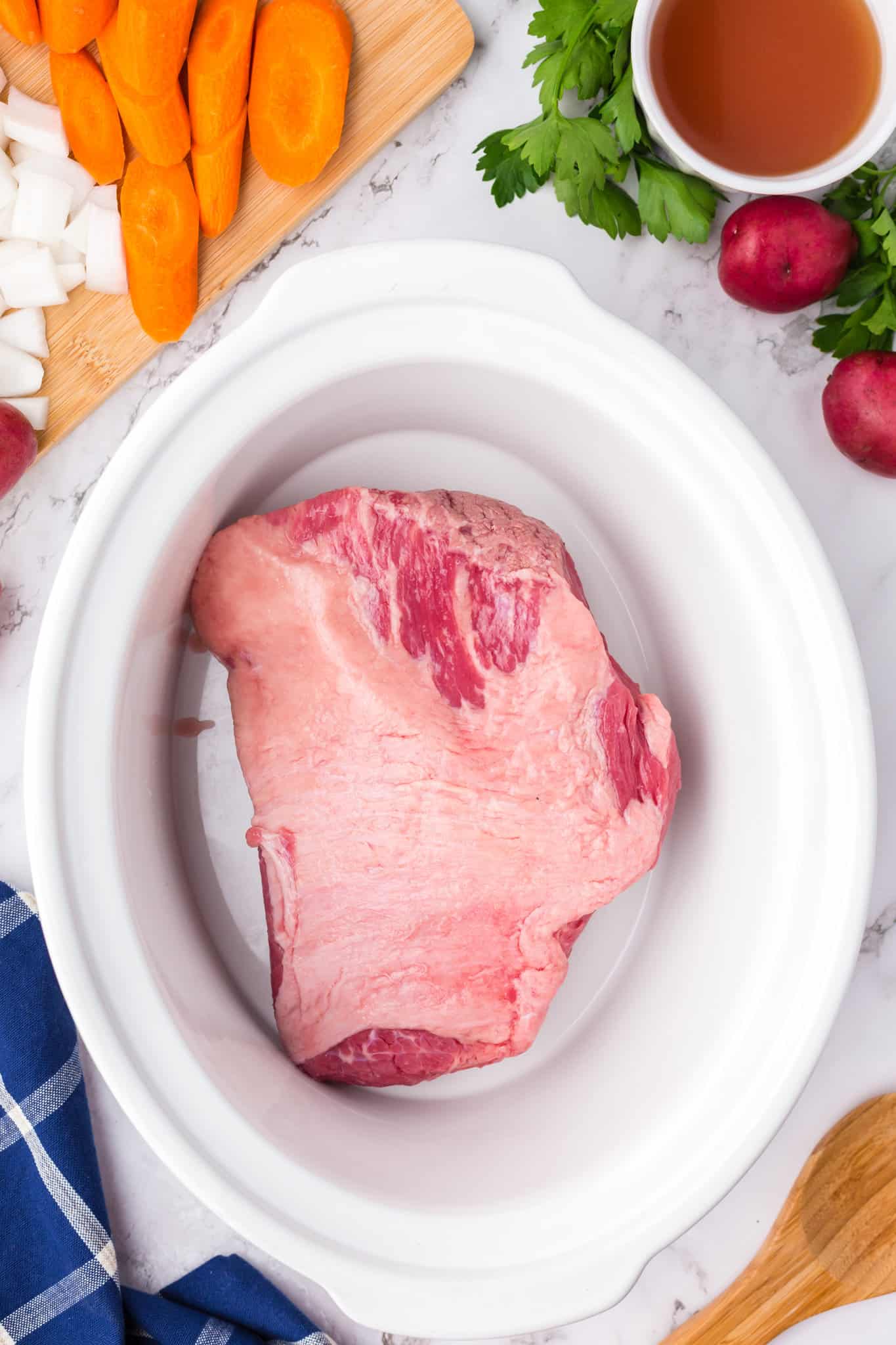 beef broth and seasoning on a beef brisket in crock pot