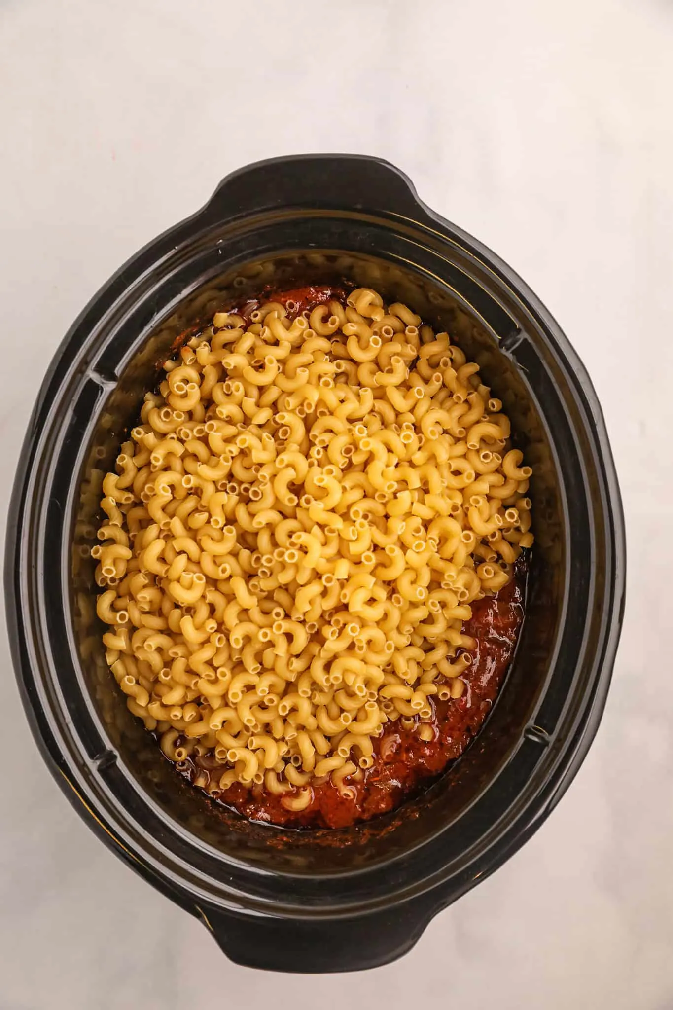 macaroni noodles added to Crock Pot with goulash sauce