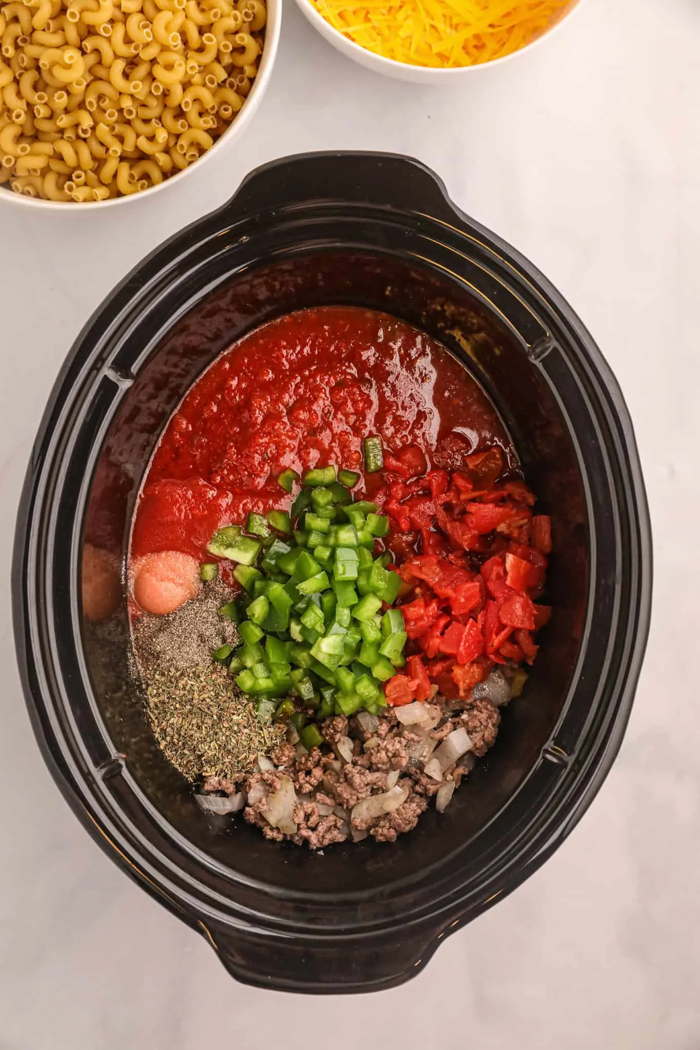 cooked ground beef, diced bell peppers, diced onions and tomato sauce in a Crock Pot