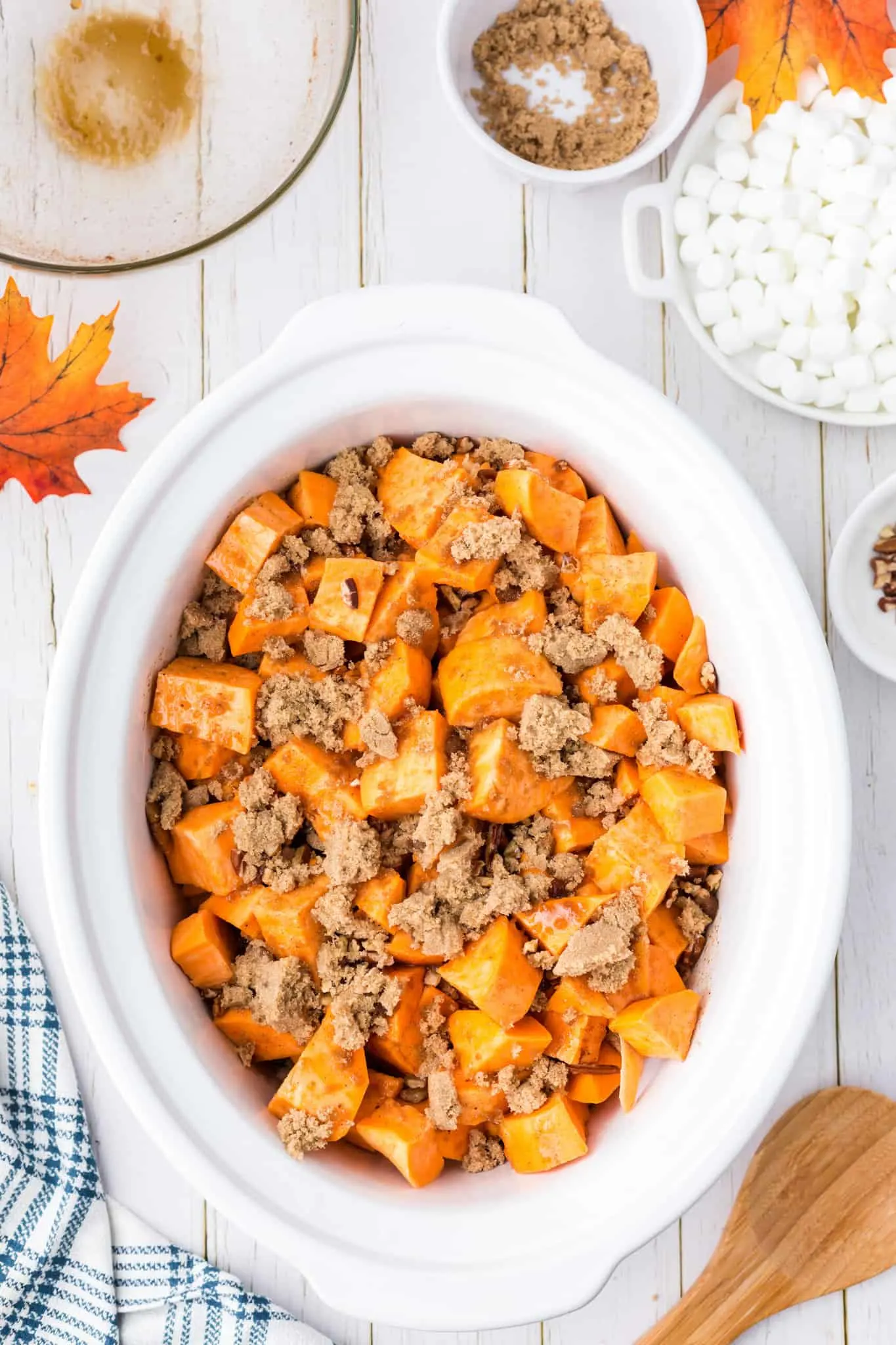 brown sugar and chopped pecans on top of cube sweet potatoes in a slow cooker