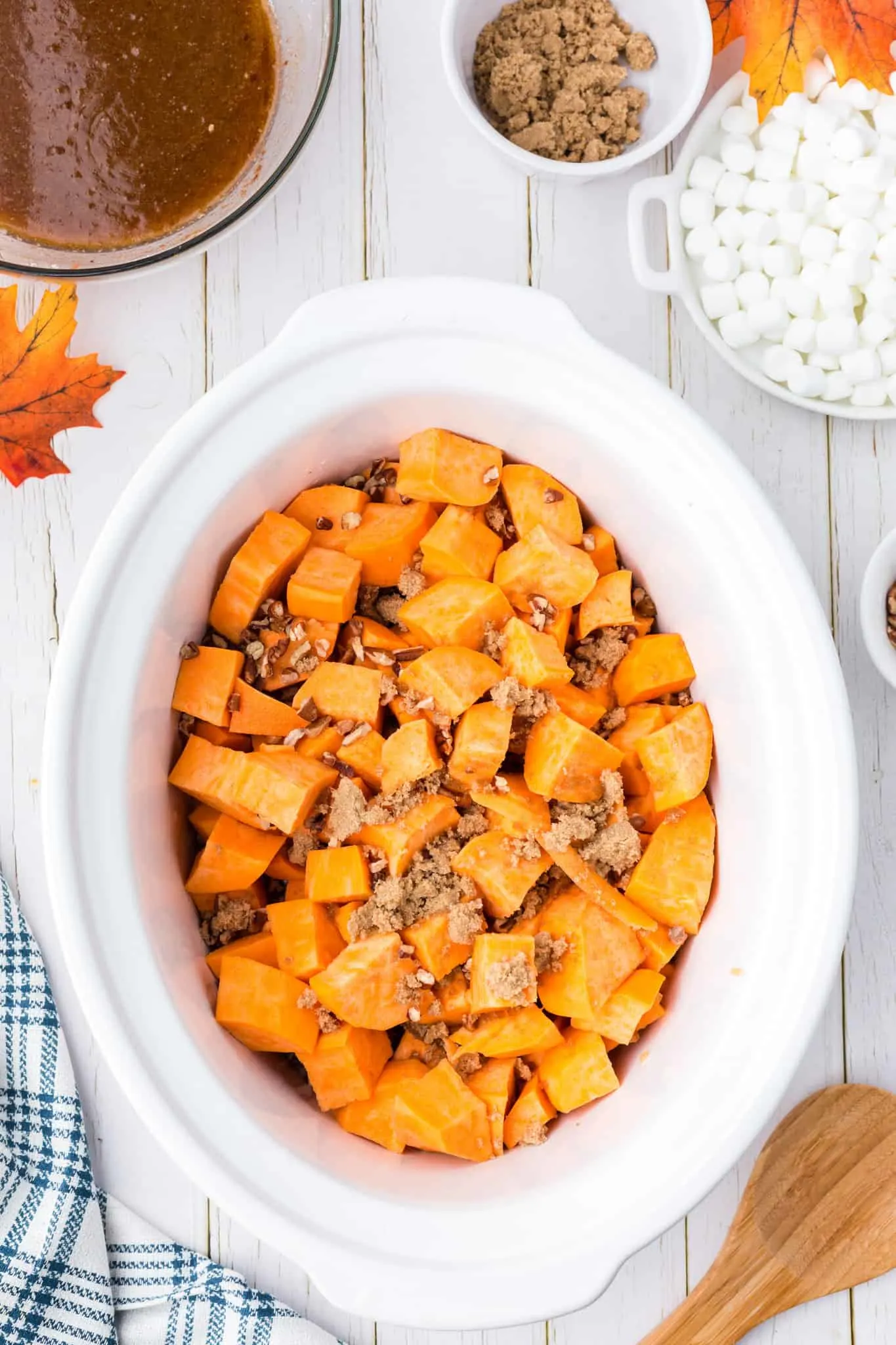 brown sugar and chopped pecans on top of cubed sweet potatoes in a crock pot