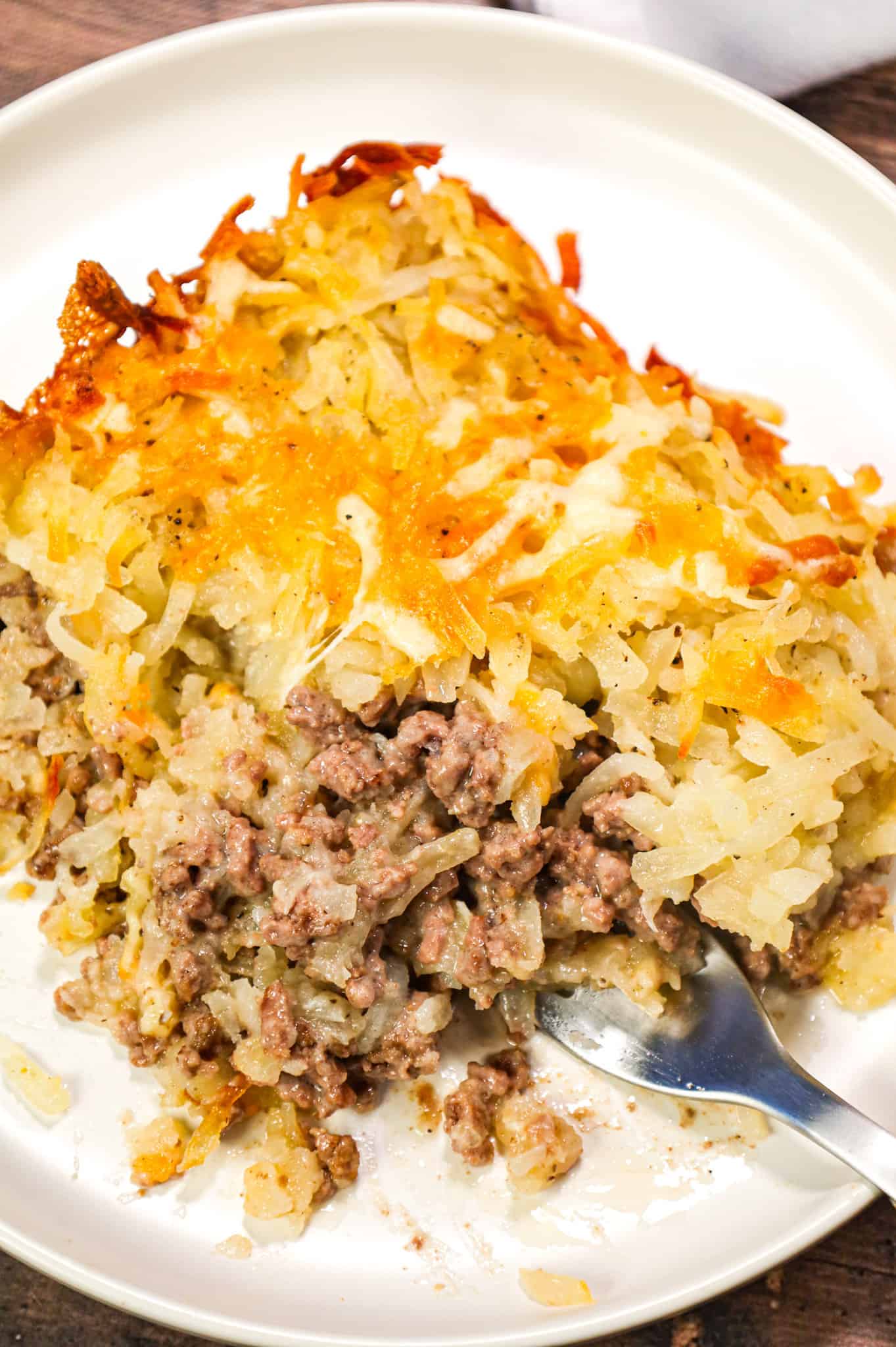 Hamburger Hashbrown Casserole is an easy ground beef dinner recipe loaded with shredded hashbrown potatoes, cream of mushroom soup and shredded mozzarella and cheddar cheese.