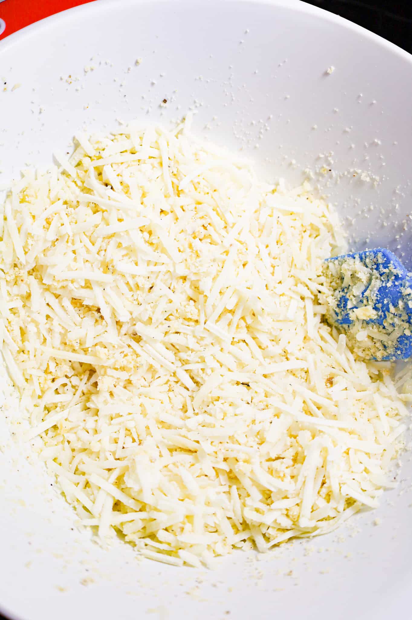 shredded hashbrown potatoes being stirred with butter and spices in a mixing bowl