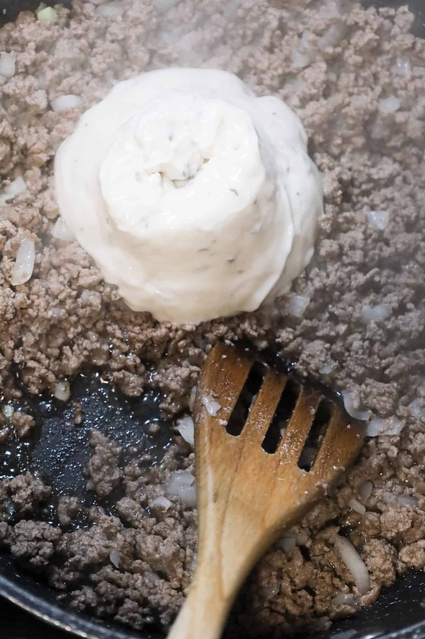 condensed cream of mushroom soup on top of cooked ground beef in a skillet