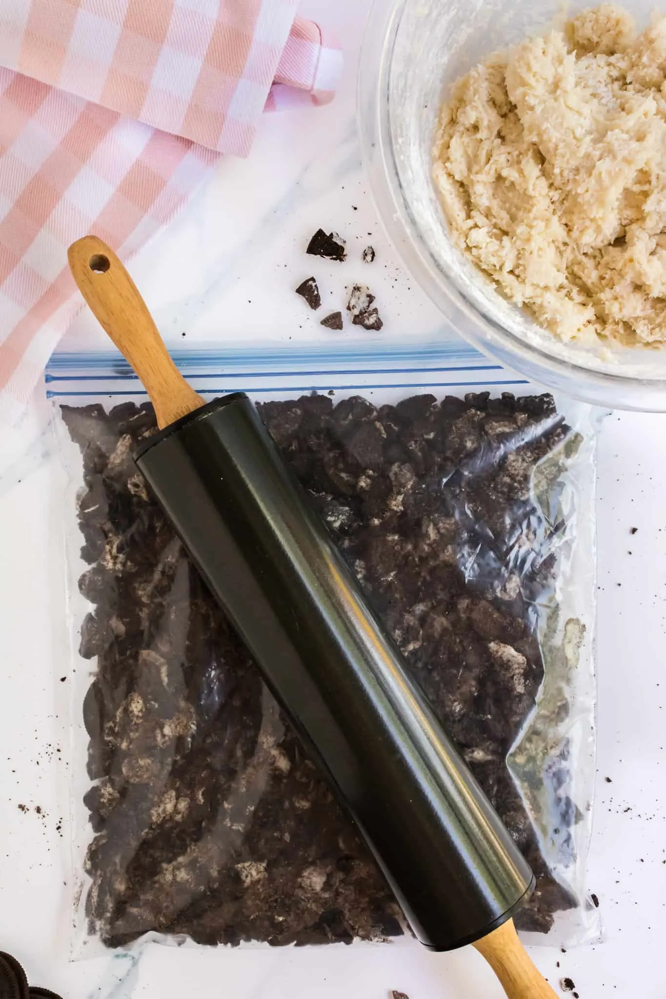 rolling pin crushing Oreo cookies in a large Ziploc bag