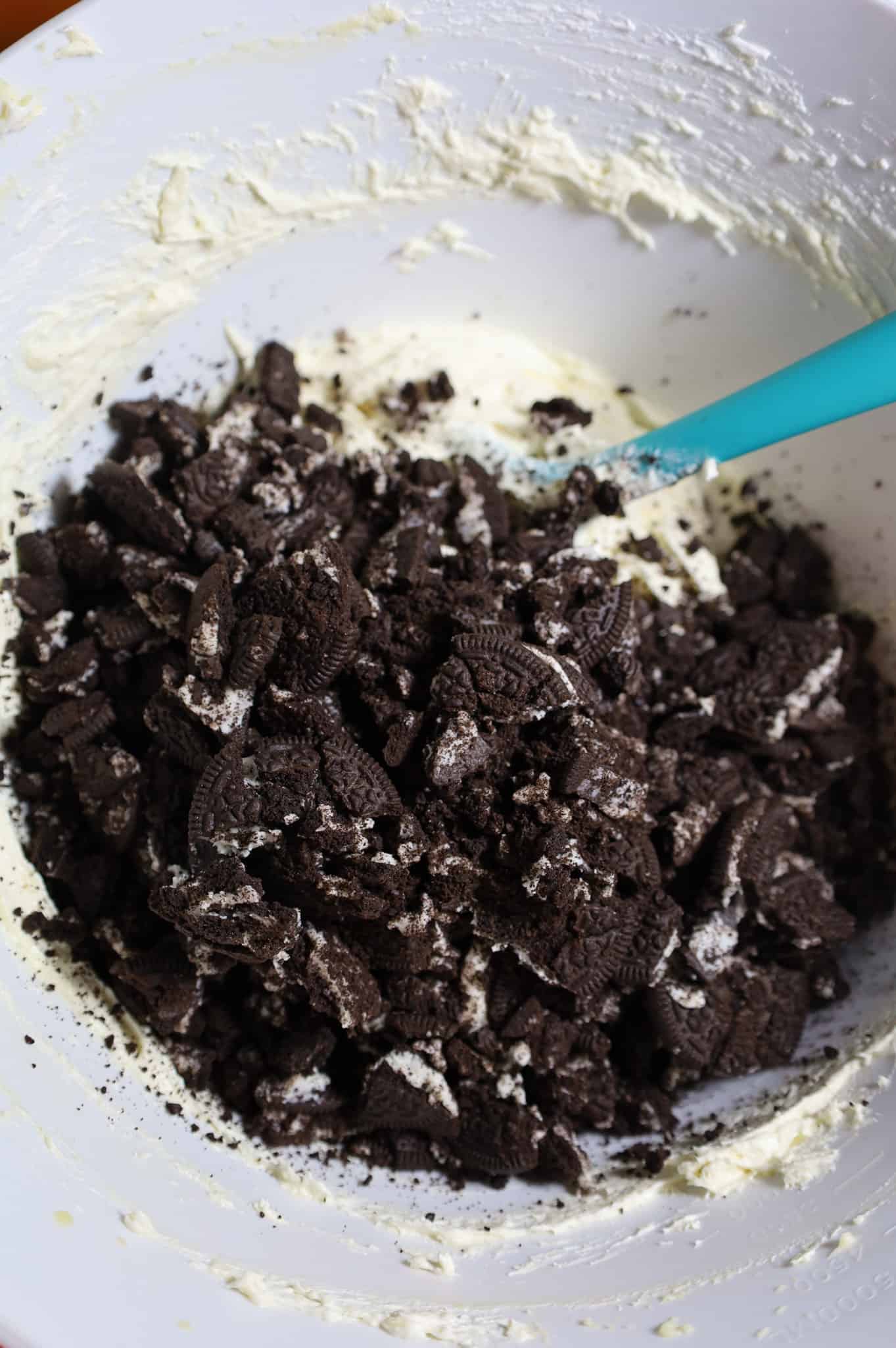 crumbled Oreo cookies on top of cream cheese mixture in a mixing bowl