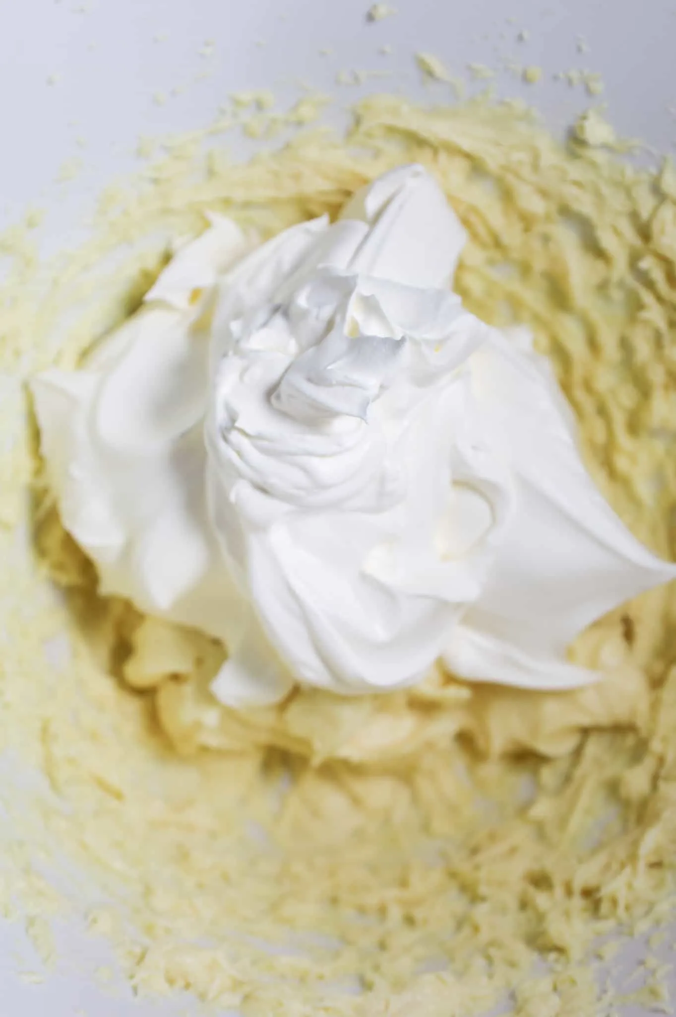Cool Whip added to mixing bowl with cream cheese and vanilla pudding mixture