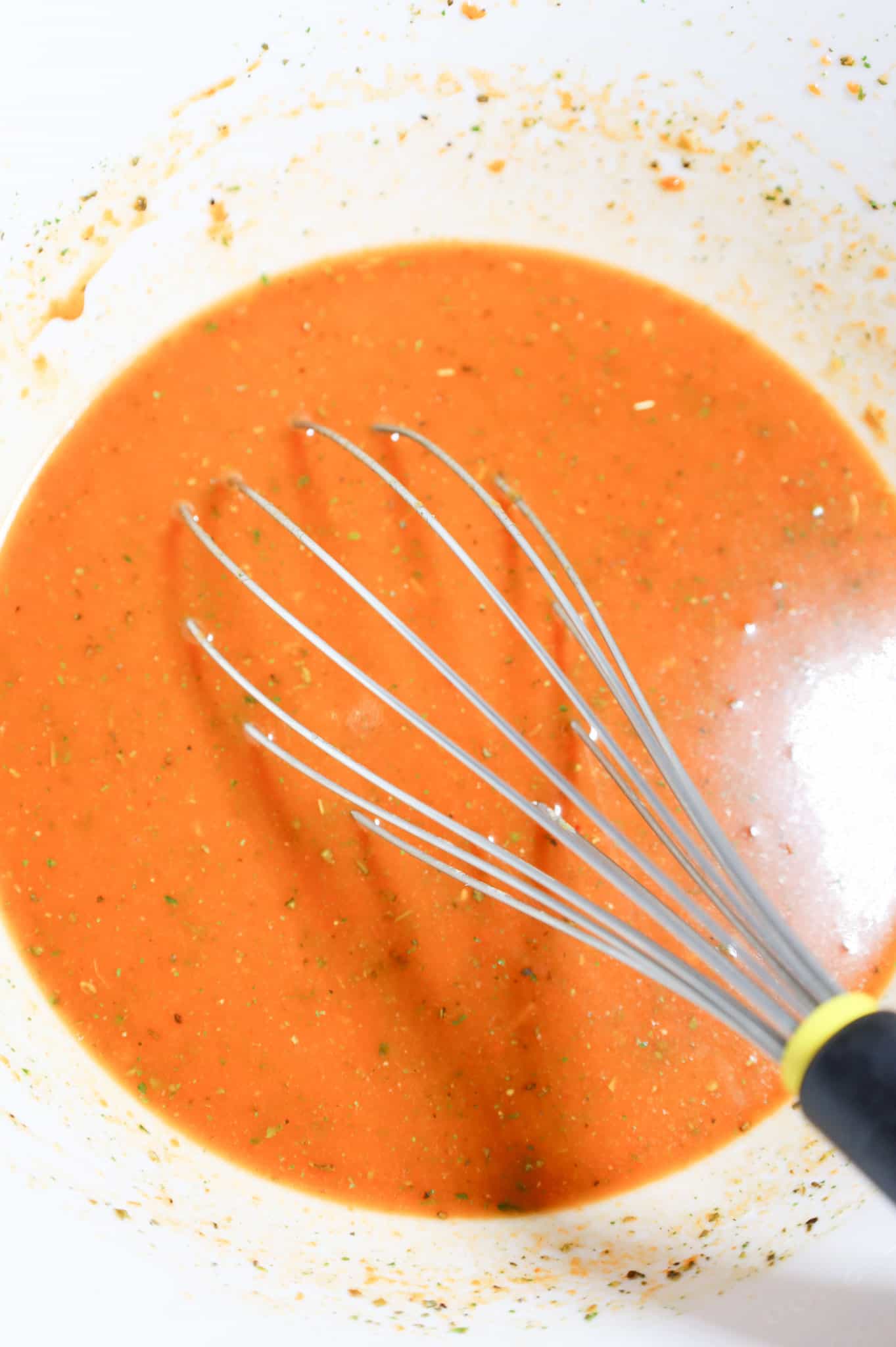 whisking together water, condensed tomato soup and spices in a mixing bowl