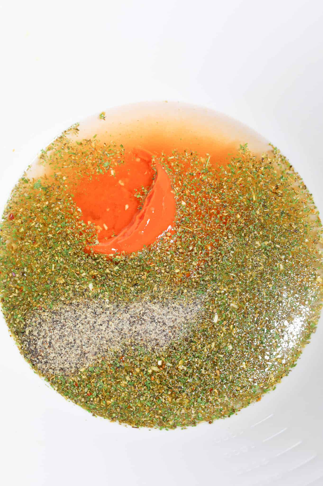Italian seasoning, water and condensed tomato soup in a mixing bowl