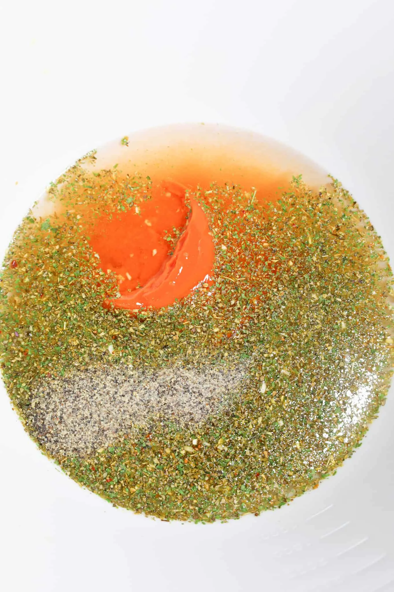 Italian seasoning, water and condensed tomato soup in a mixing bowl