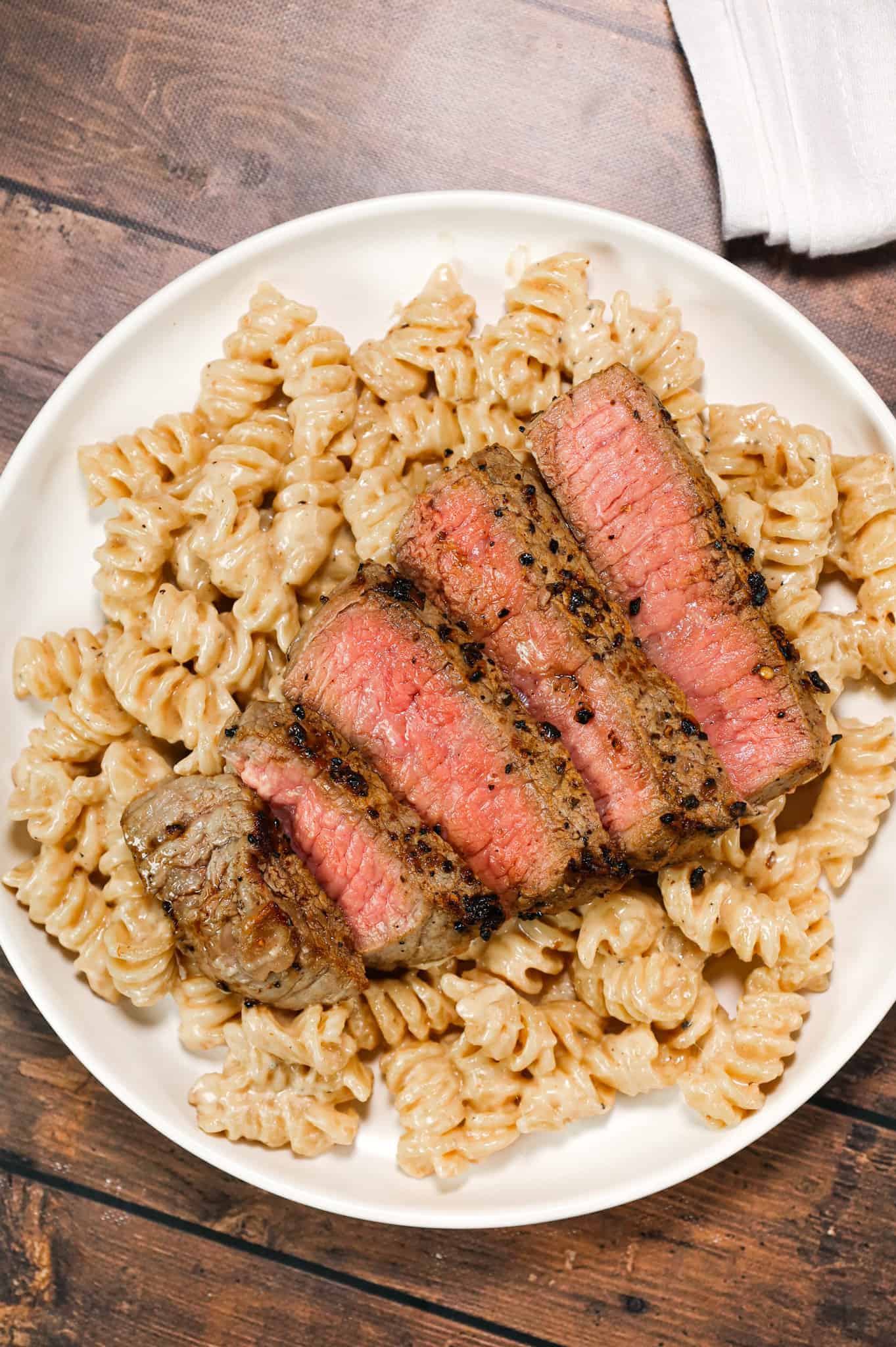 Steak Alfredo is an easy dinner recipe with creamy garlic parmesan pasta topped with tender slices of eye of round steak.