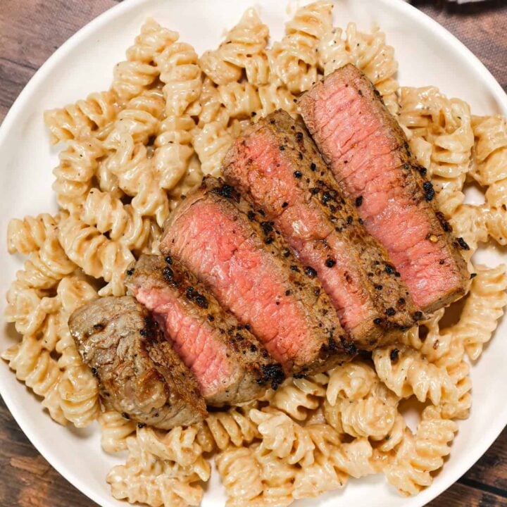 Steak Alfredo is an easy dinner recipe with creamy garlic parmesan pasta topped with tender slices of eye of round steak.