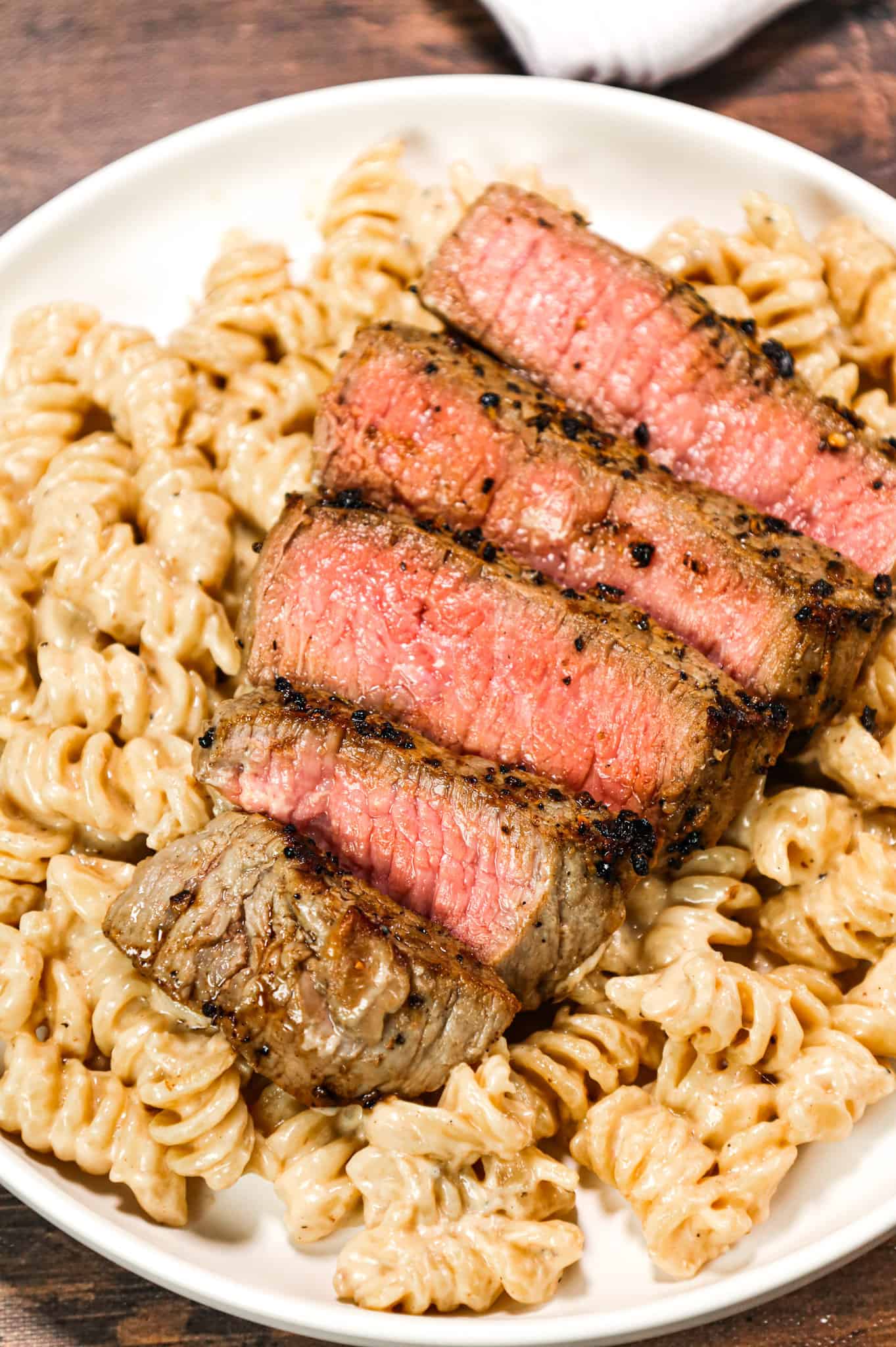 Steak Alfredo is an easy dinner recipe with creamy garlic parmesan pasta topped with tender slices of eye of round steak.