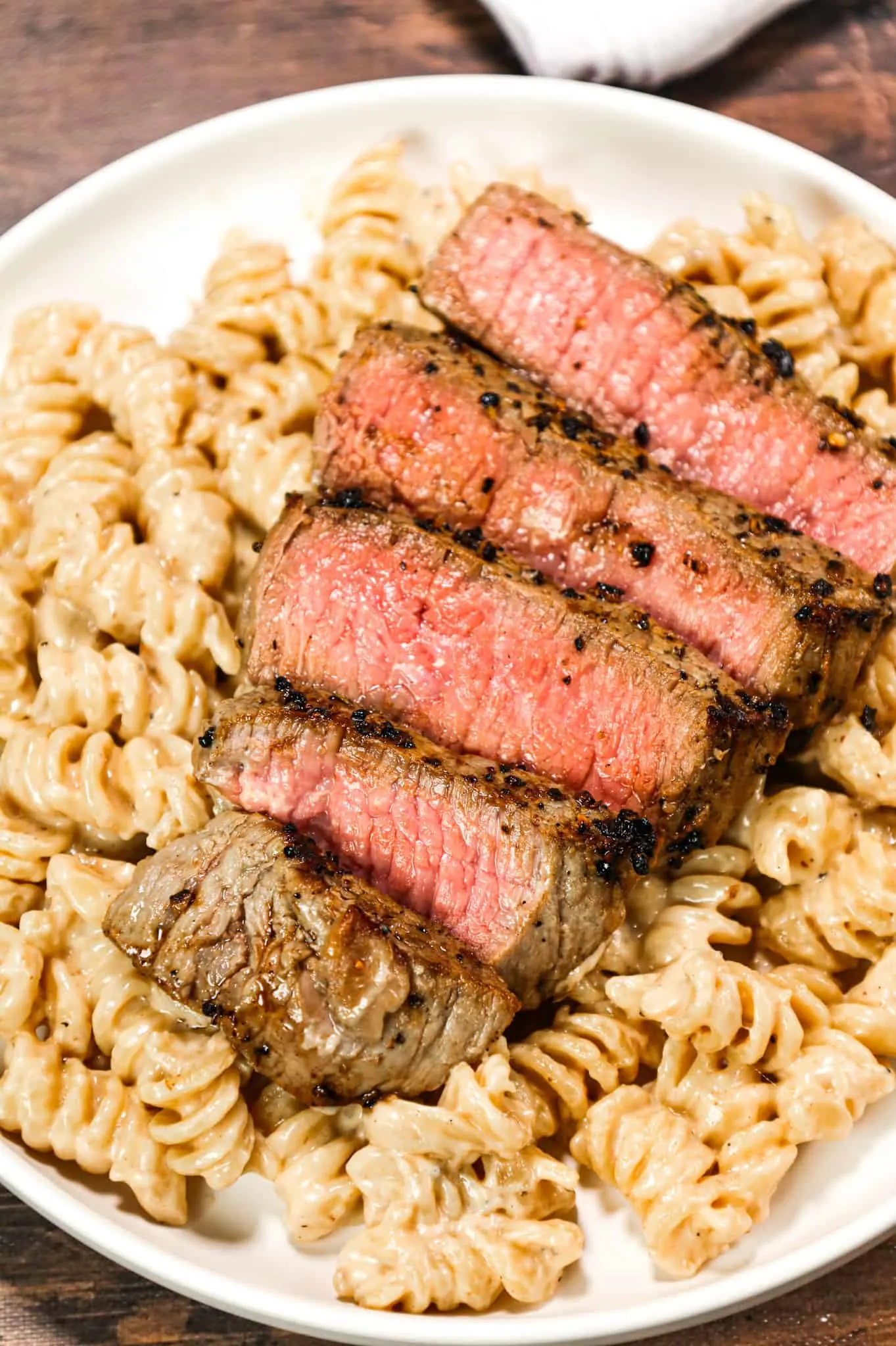 Steak Alfredo is an easy dinner recipe with creamy garlic parmesan pasta topped with tender slices of eye of round steak.