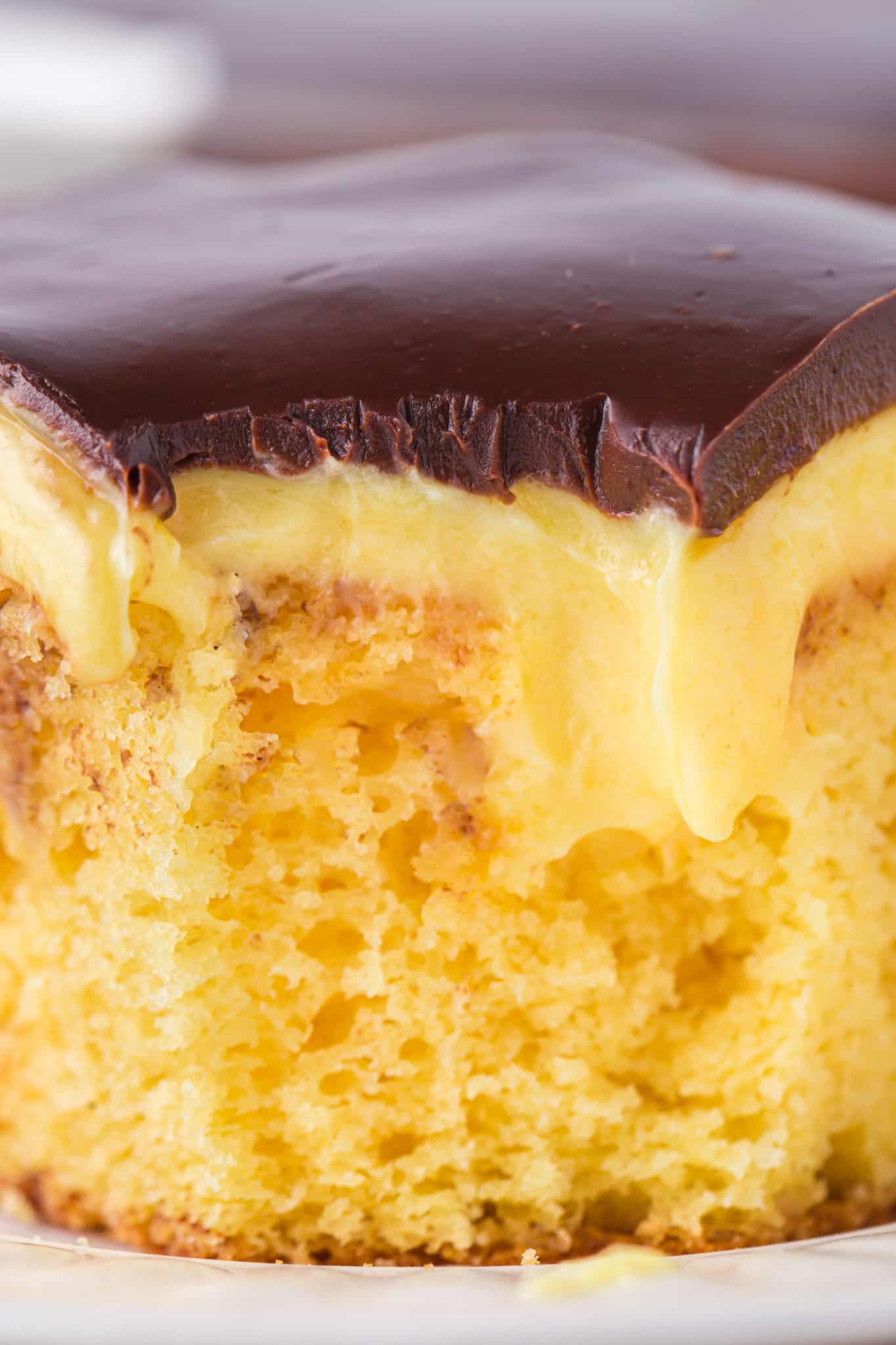 Boston Cream Poke Cake is a moist and delicious dessert recipe made with boxed yellow cake mix covered in creamy vanilla pudding and topped with chocolate ganache.