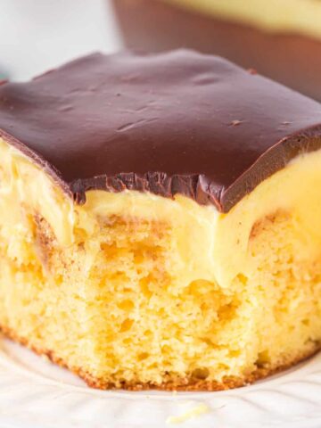 Boston Cream Poke Cake is a moist and delicious dessert recipe made with boxed yellow cake mix covered in creamy vanilla pudding and topped with chocolate ganache.