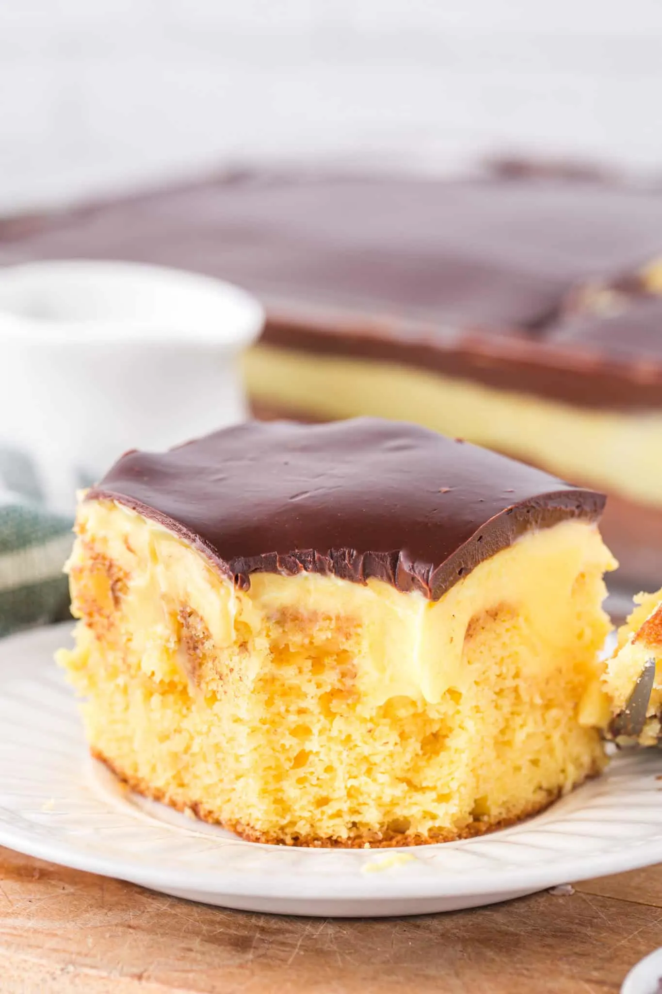 Boston Cream Poke Cake is a moist and delicious dessert recipe made with boxed yellow cake mix covered in creamy vanilla pudding and topped with chocolate ganache.