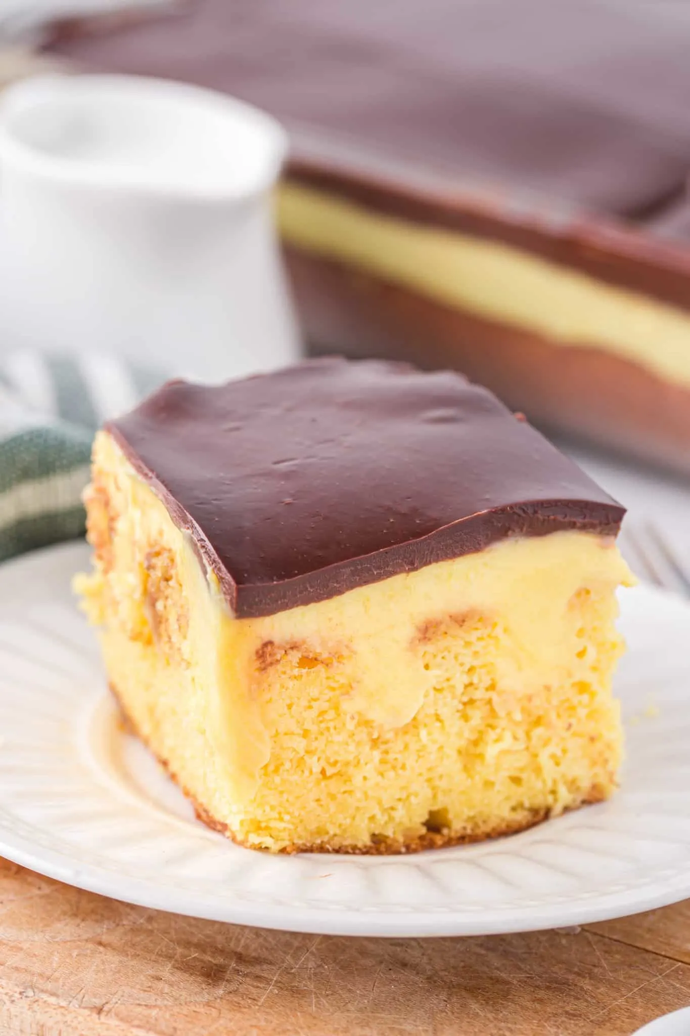 Boston Cream Poke Cake is a moist and delicious dessert recipe made with boxed yellow cake mix covered in creamy vanilla pudding and topped with chocolate ganache.