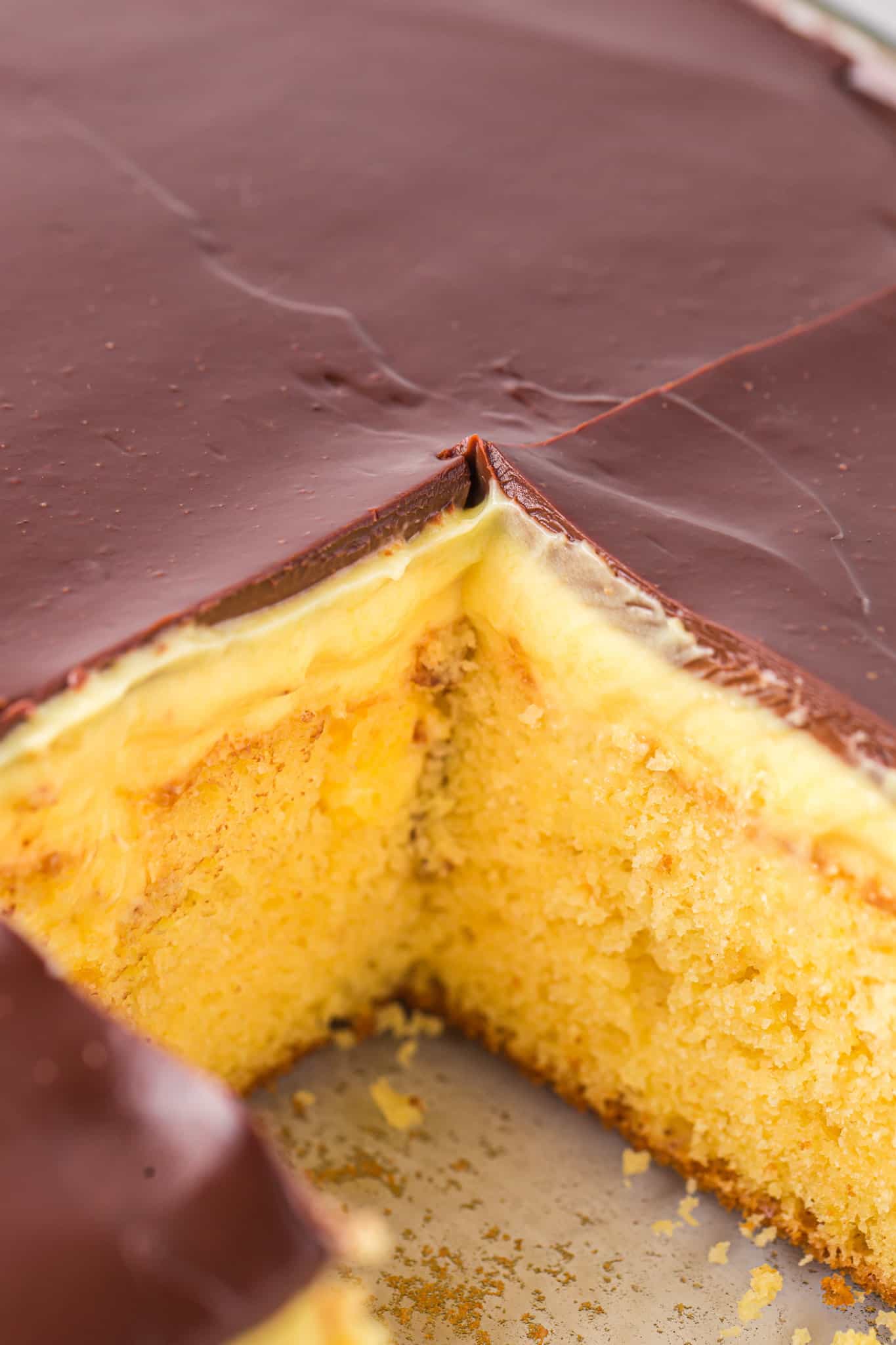 Boston Cream Poke Cake is a moist and delicious dessert recipe made with boxed yellow cake mix covered in creamy vanilla pudding and topped with chocolate ganache.