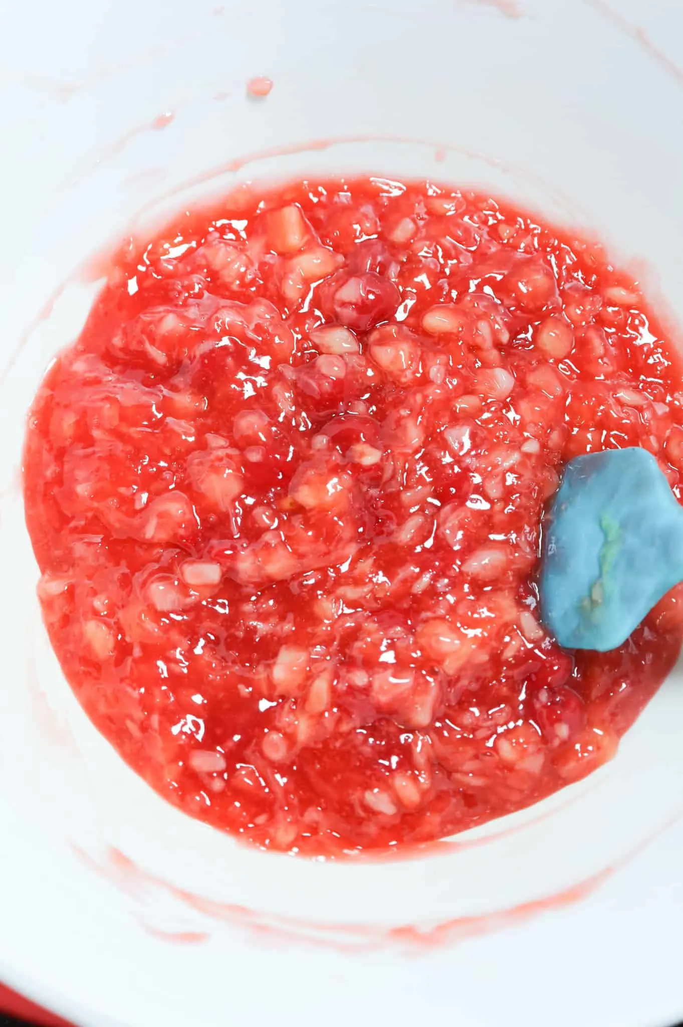 cherry pie filling, pineapple and pudding mixture in a mixing bowl