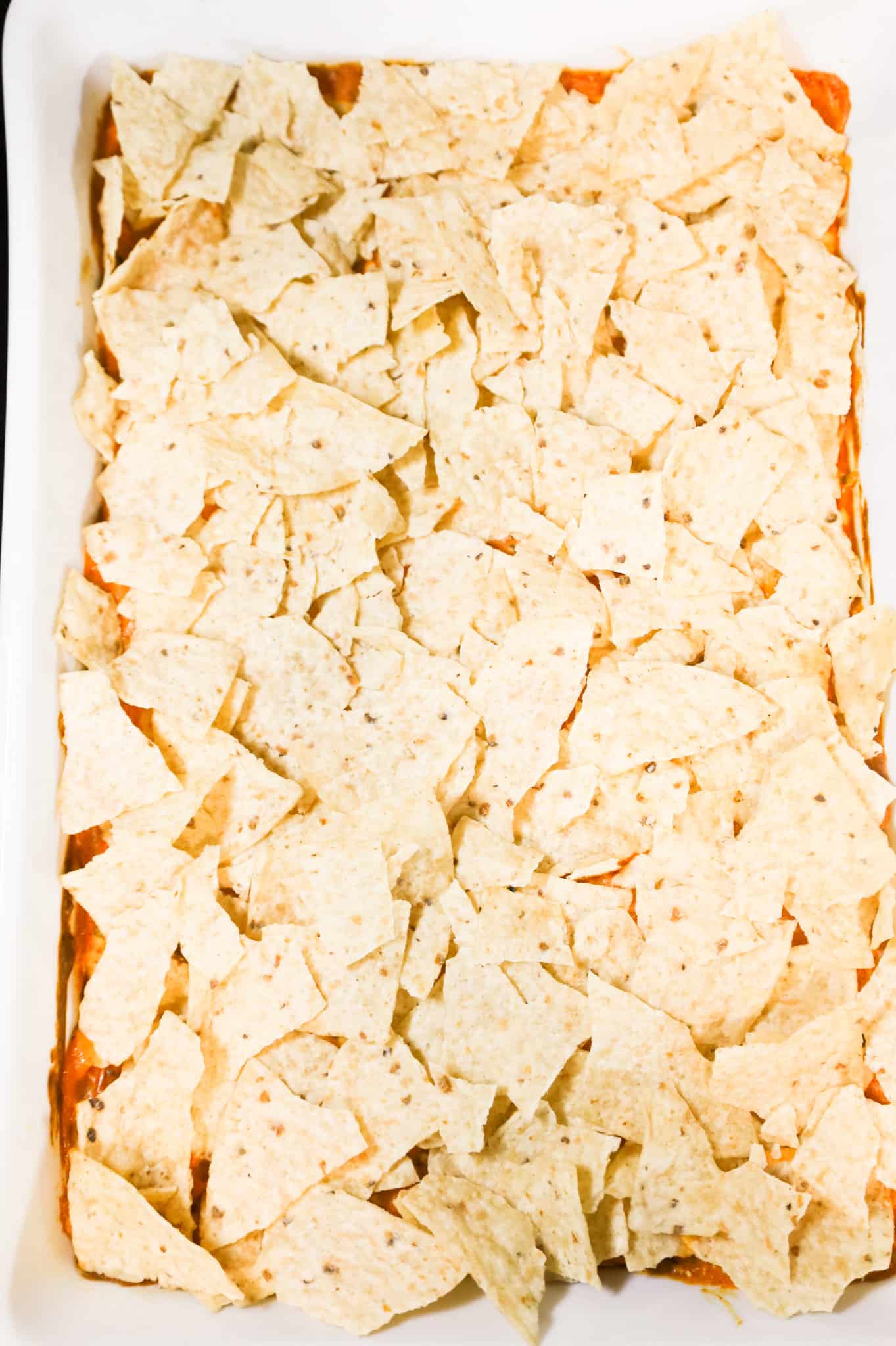 crumbled tortilla chips on top of creamy chicken mixture in a baking dish