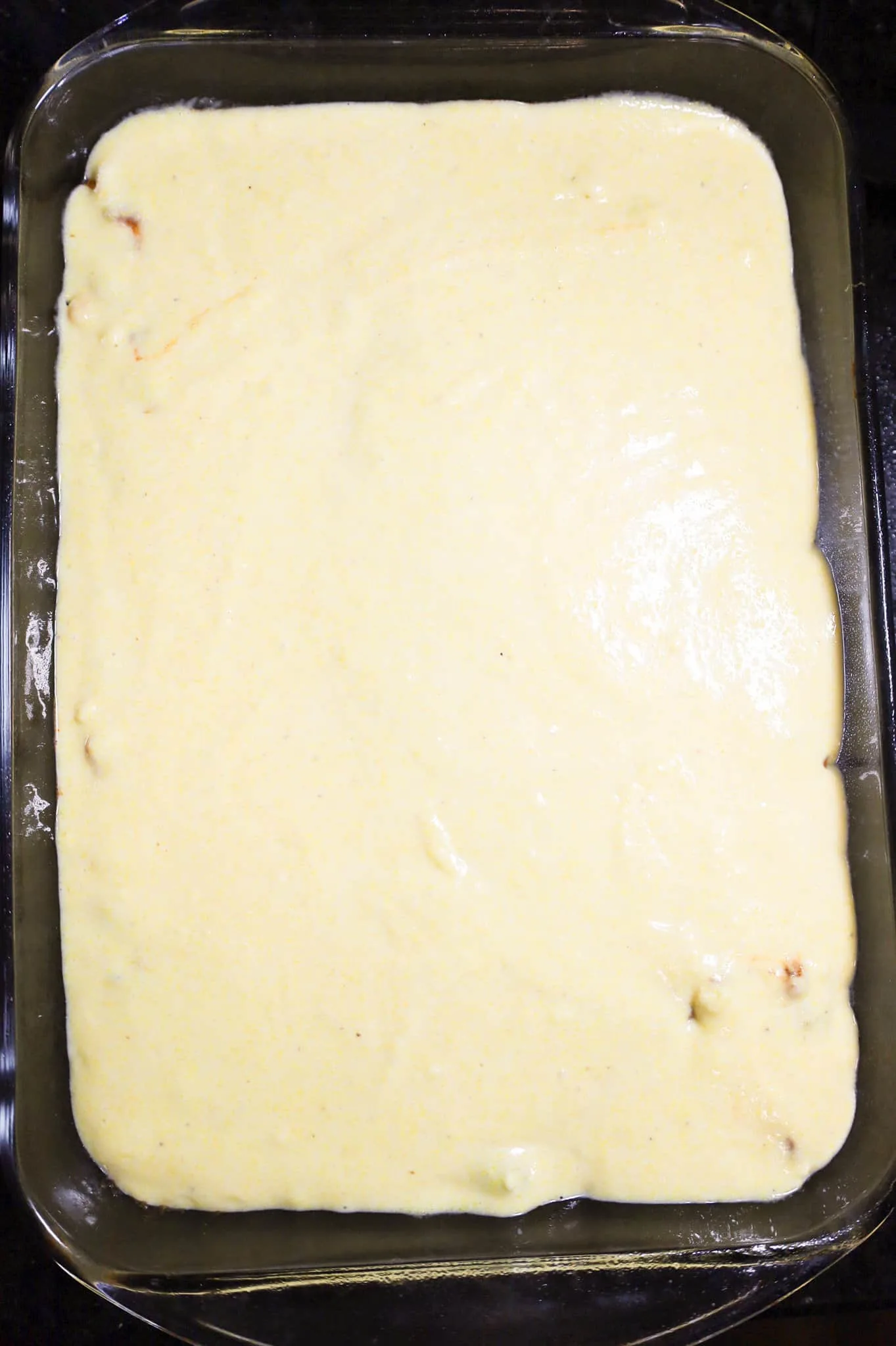 cornbread batter on top of ground beef mixture in a baking dish